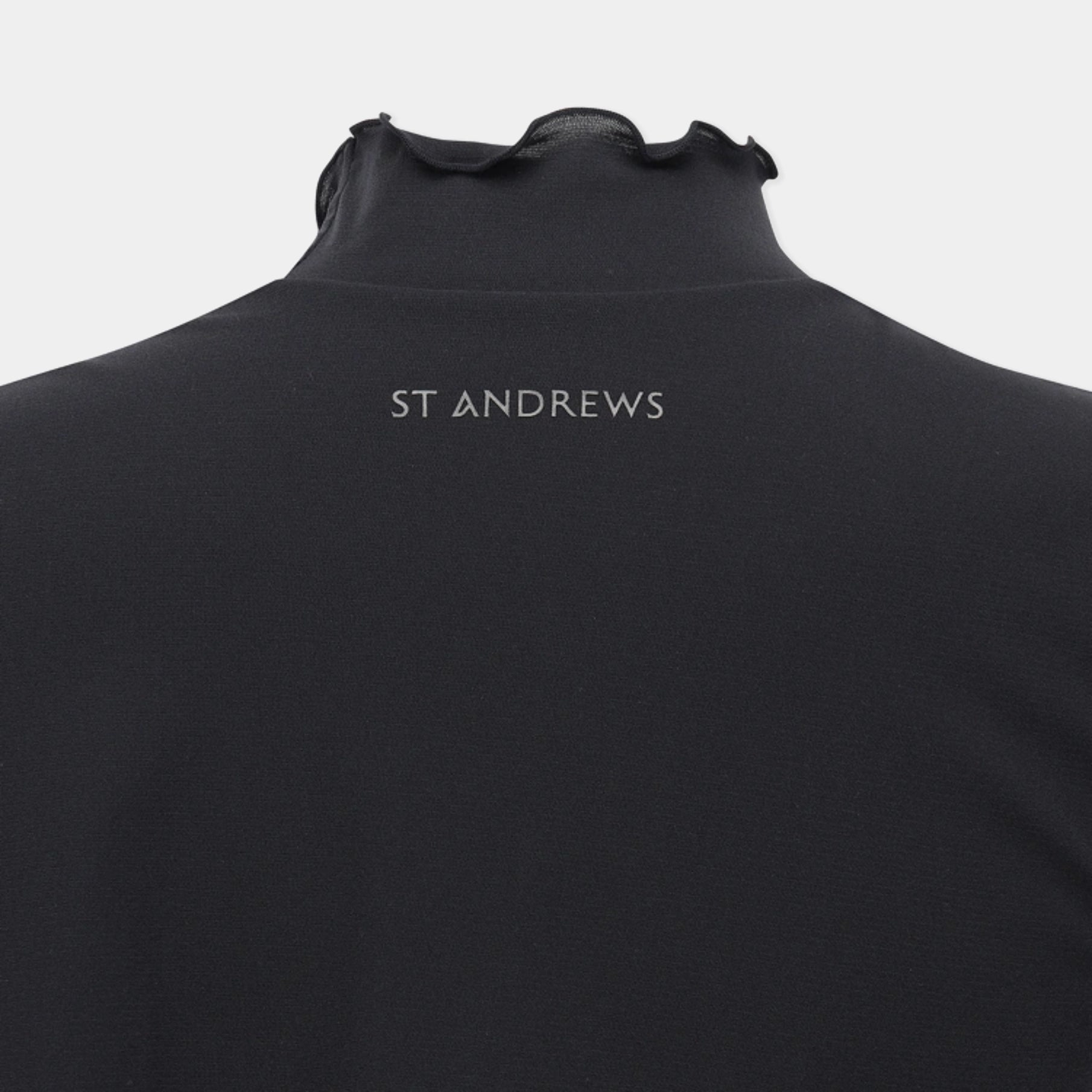 Close-up of the back of a black high-neck top with 'ST ANDREWS' printed in white text at the center, shown on a light gray background.