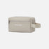 A light beige toiletry bag with a top zipper, featuring the brand name &