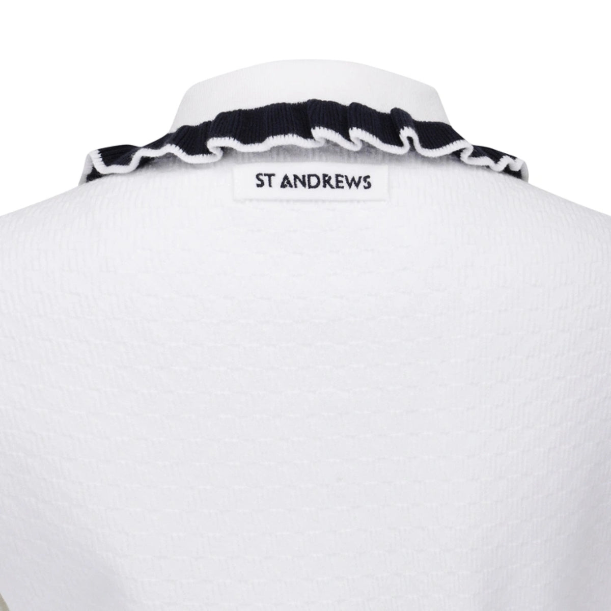 Close-up of the back of a white textured St Andrews polo shirt, showing a black ruffled collar with white trim and a white neck label with black text reading 'ST ANDREWS'.
