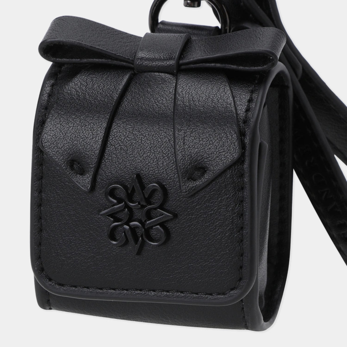 A black textured faux-leather pouch with a bow detail on top and a black metal logo emblem on the front, shown against a light gray background.