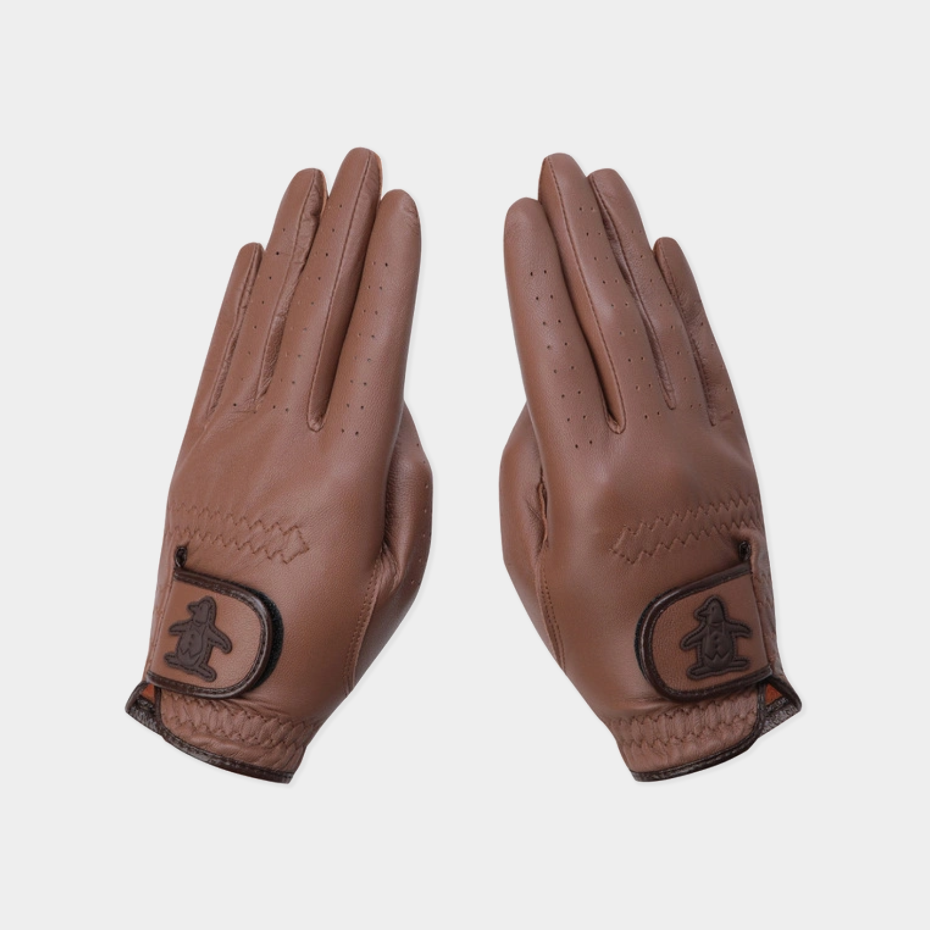 A pair of brown leather golf gloves shown flat against a light gray background, featuring a stitched wrist strap with an embossed logo.