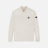 An off-white long-sleeve polo shirt with a small embroidered shield logo on the left chest and a black brand patch on the right sleeve, shown against a light gray background.
