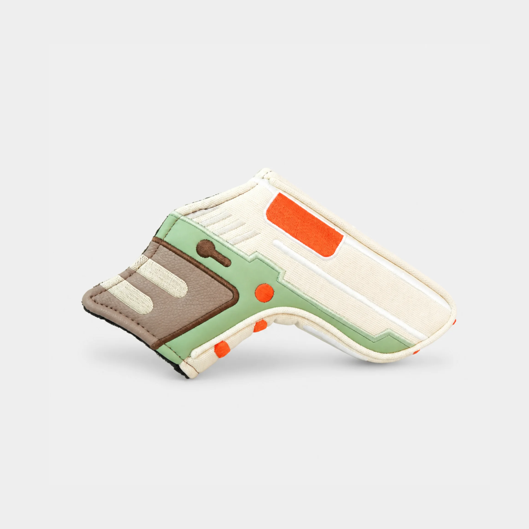 A miniature replica of a sci-fi blaster pistol, styled with light green, off-white, brown, and orange panels, displayed on a clean light gray background.
