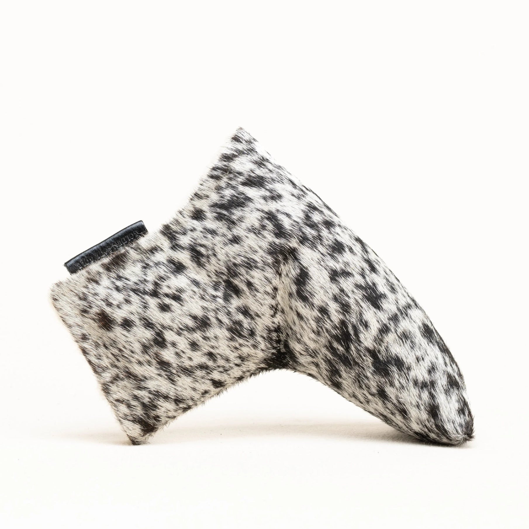 A putter cover covered in a black and white dalmatian-patterned faux fur material, shown from a side profile on a clean white background.