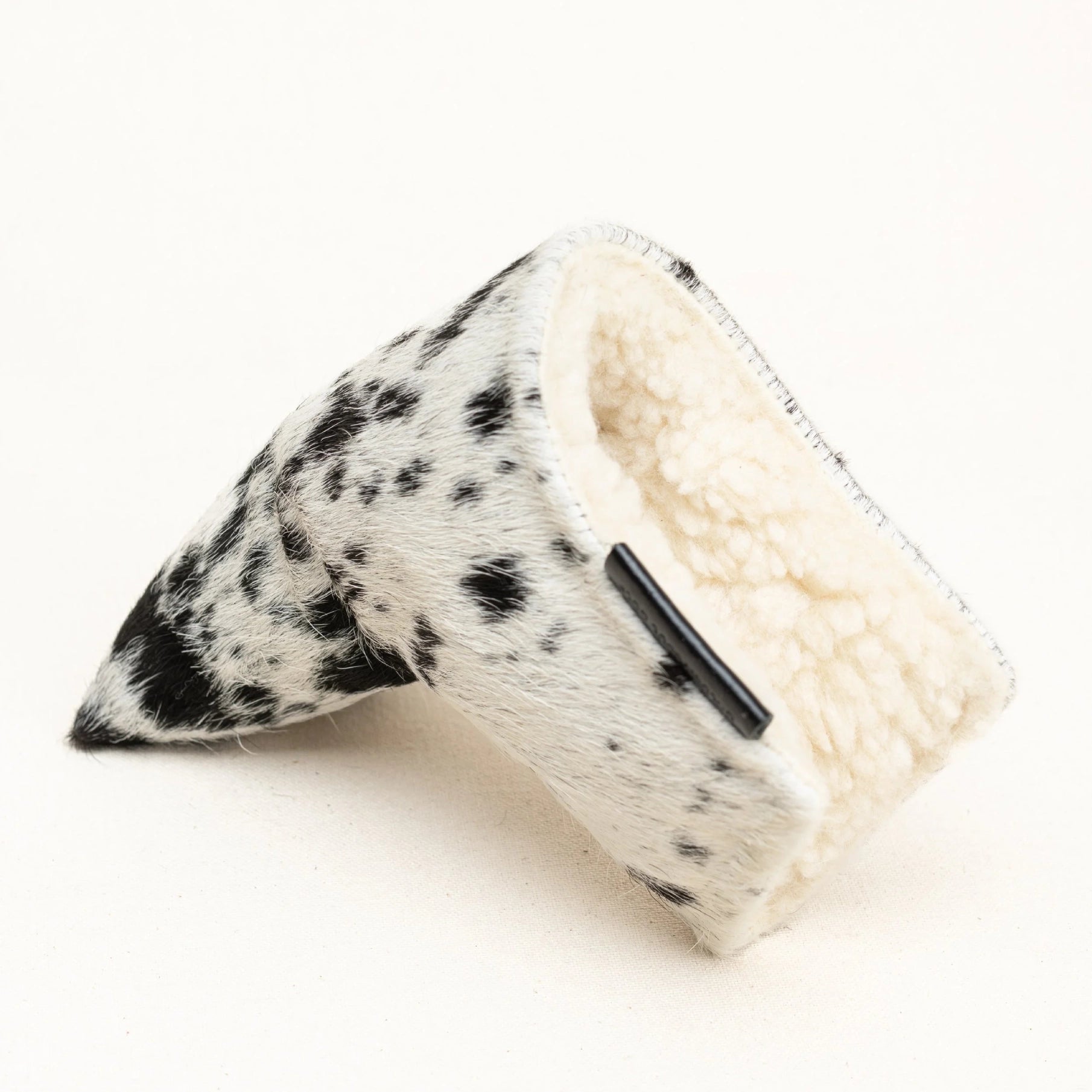A putter cover with a black and white cow print exterior and a soft cream fleece lining, shown on a plain white background.