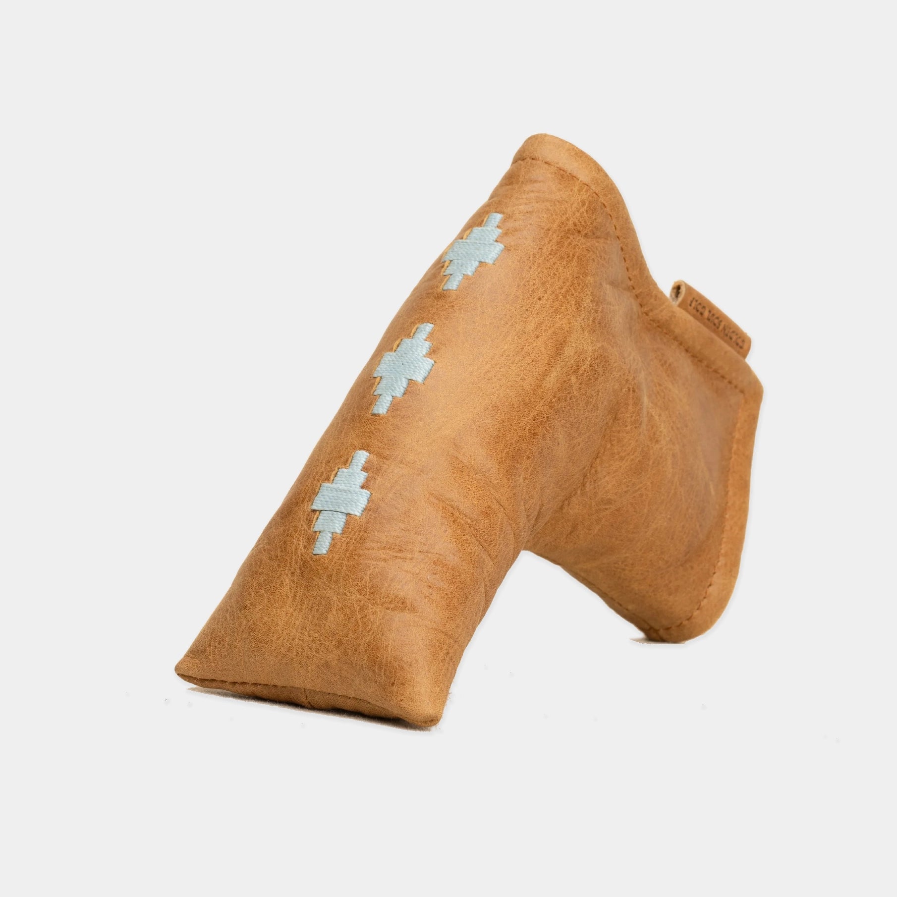 A tan leather golf putter headcover with three light blue geometric woven patterns, shown on a plain light gray background.
