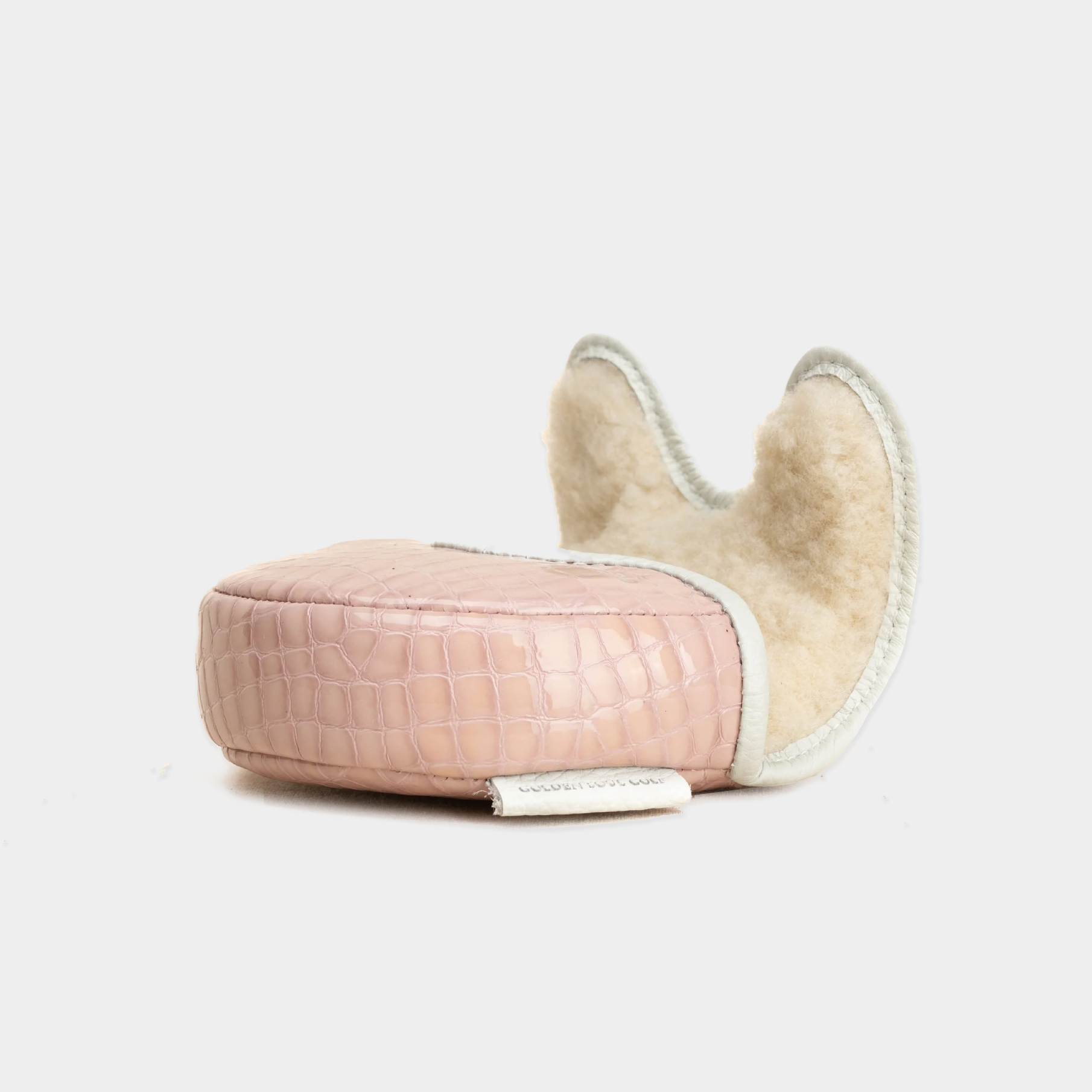 A pink crocodile-embossed OZ1 Putter Cover with a cream-colored sheepskin lining and a small white fabric tag, photographed on a clean white background.