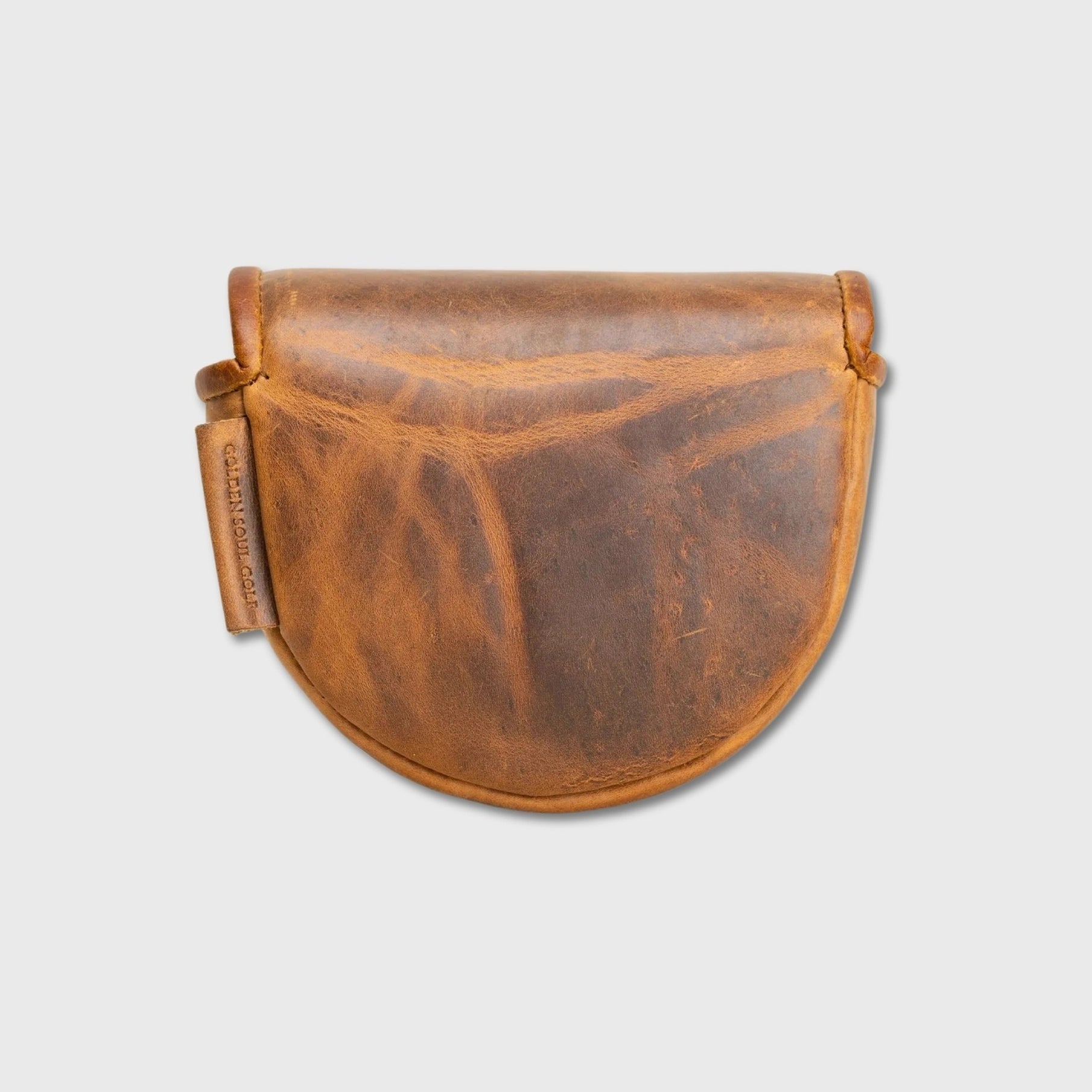A distressed brown leather OZ1 putter cover with a curved bottom and a small hanging leather tag, shown against a light gray background.