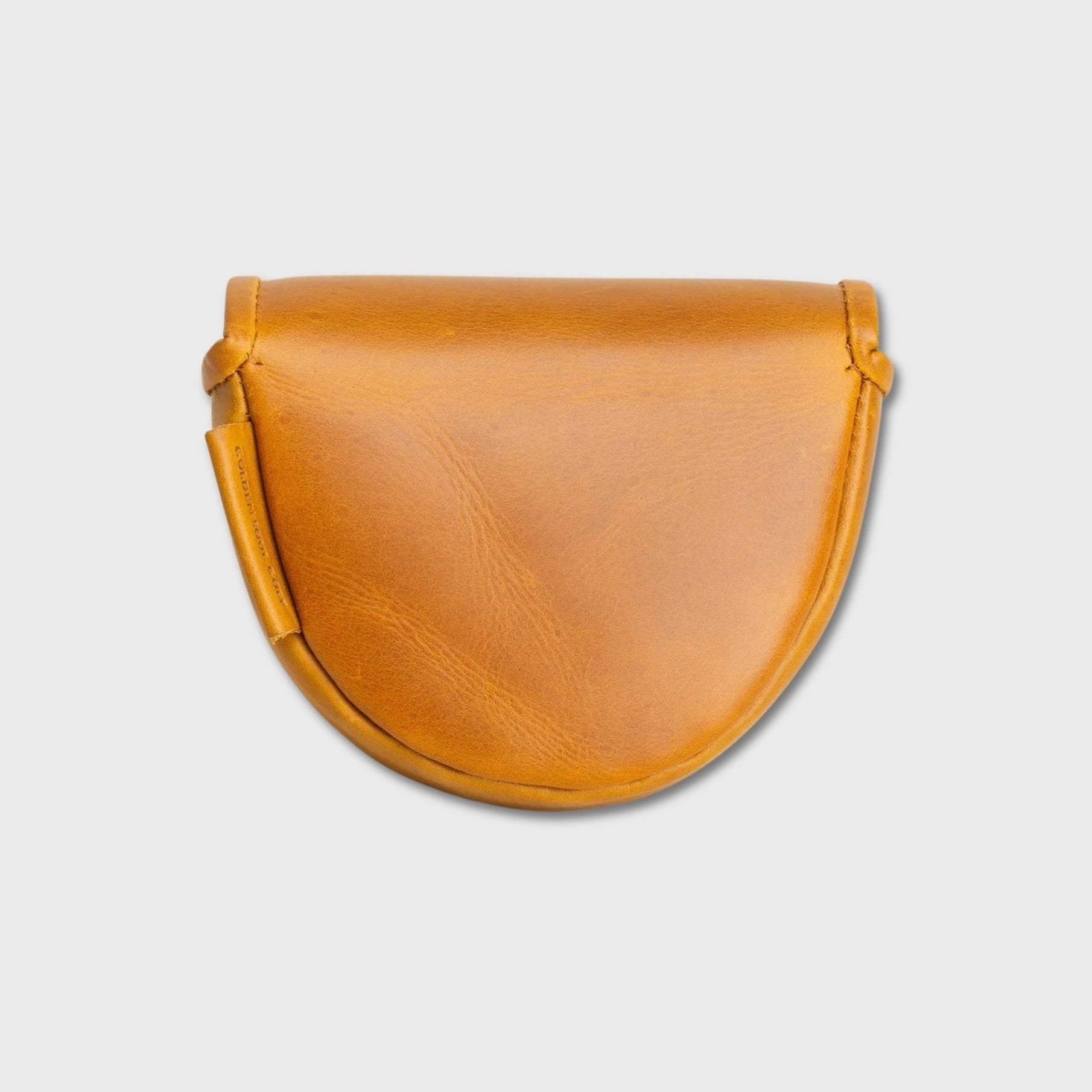A semi-circular tan leather OZ1 putter cover with a curved bottom and a strap detail on the left side, shown against a light gray background.
