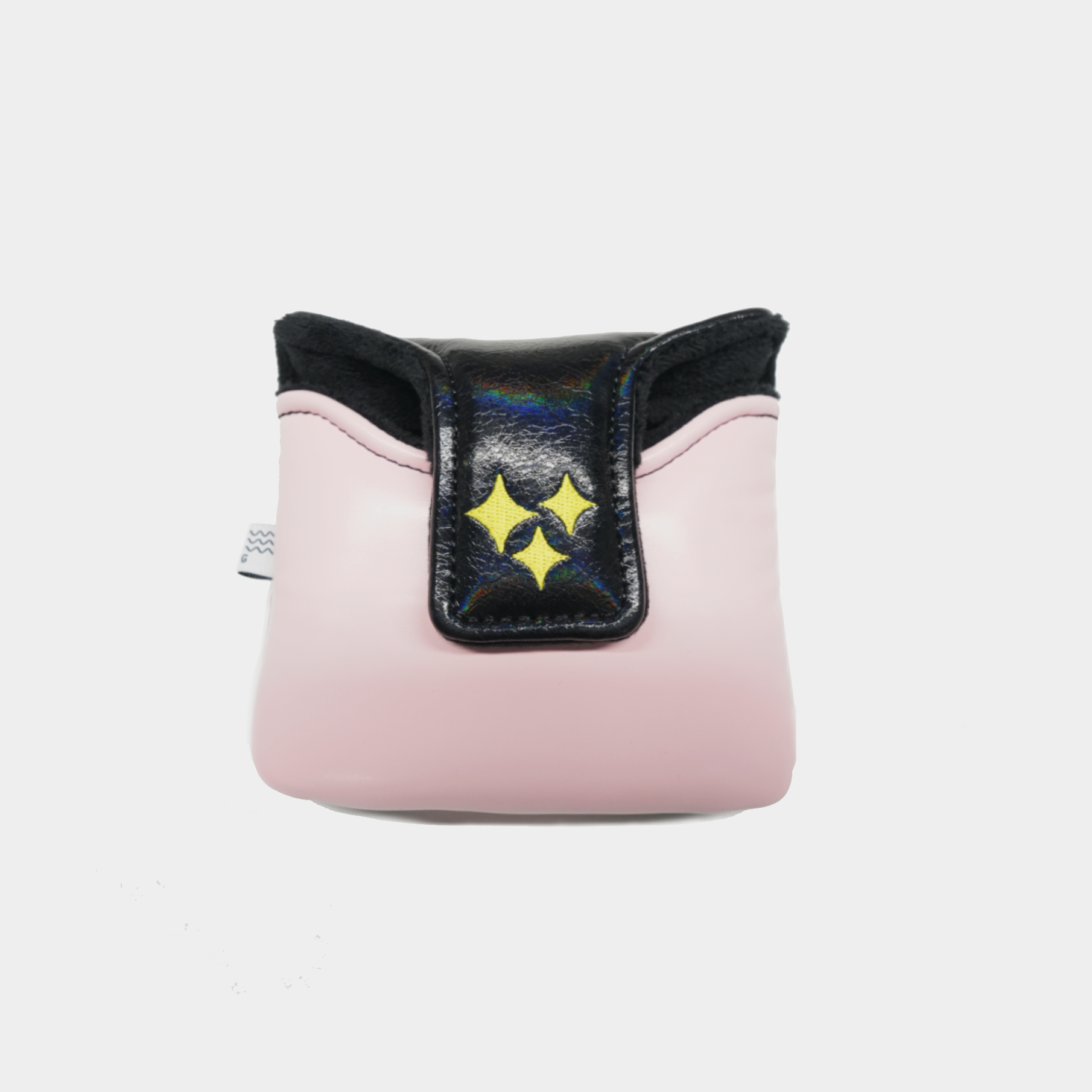 A pink mallet putter cover with a black flap featuring three yellow star-like cutouts, photographed against a light gray background.