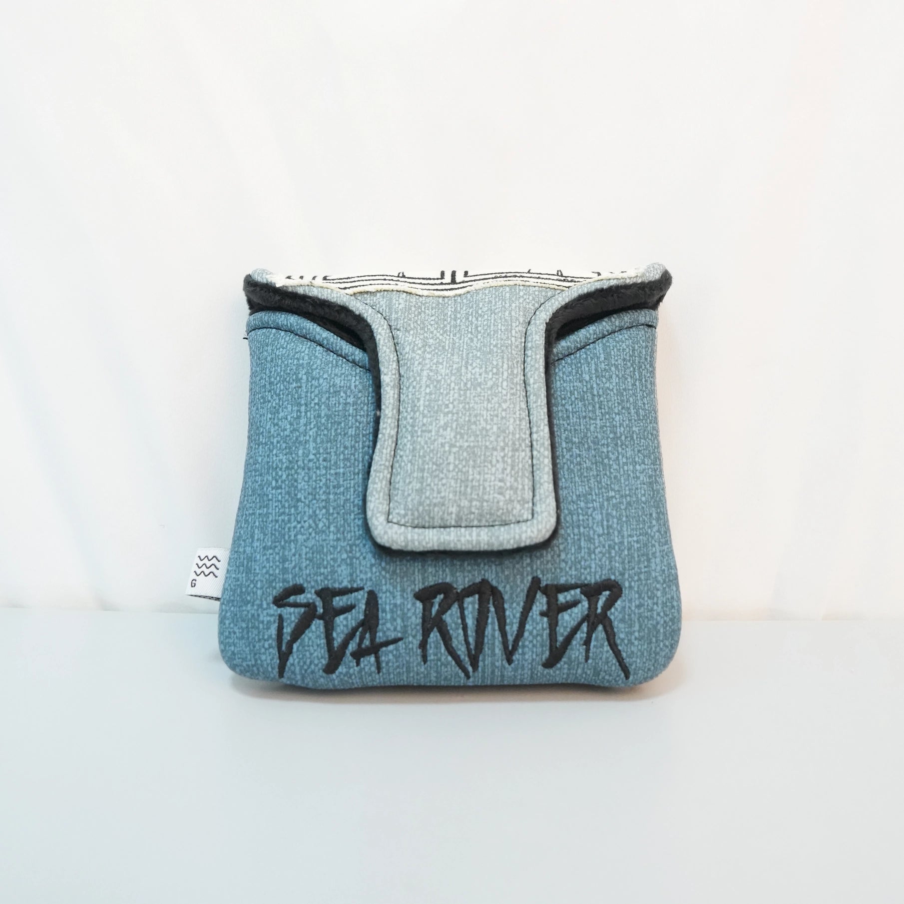 A light blue denim pouch with a central flap detail and the words 'SEA ROVER' embroidered in black across the front, set against a plain white background.