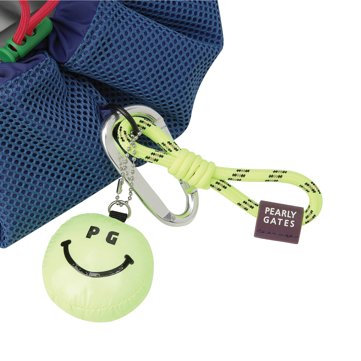 A Pearly Gates brand carabiner keychain set shown attached to a blue mesh bag. The set includes a lime green round inflatable pouch with a black smiley face, a silver carabiner, a matching lime green braided rope, and a small brown brand tag.