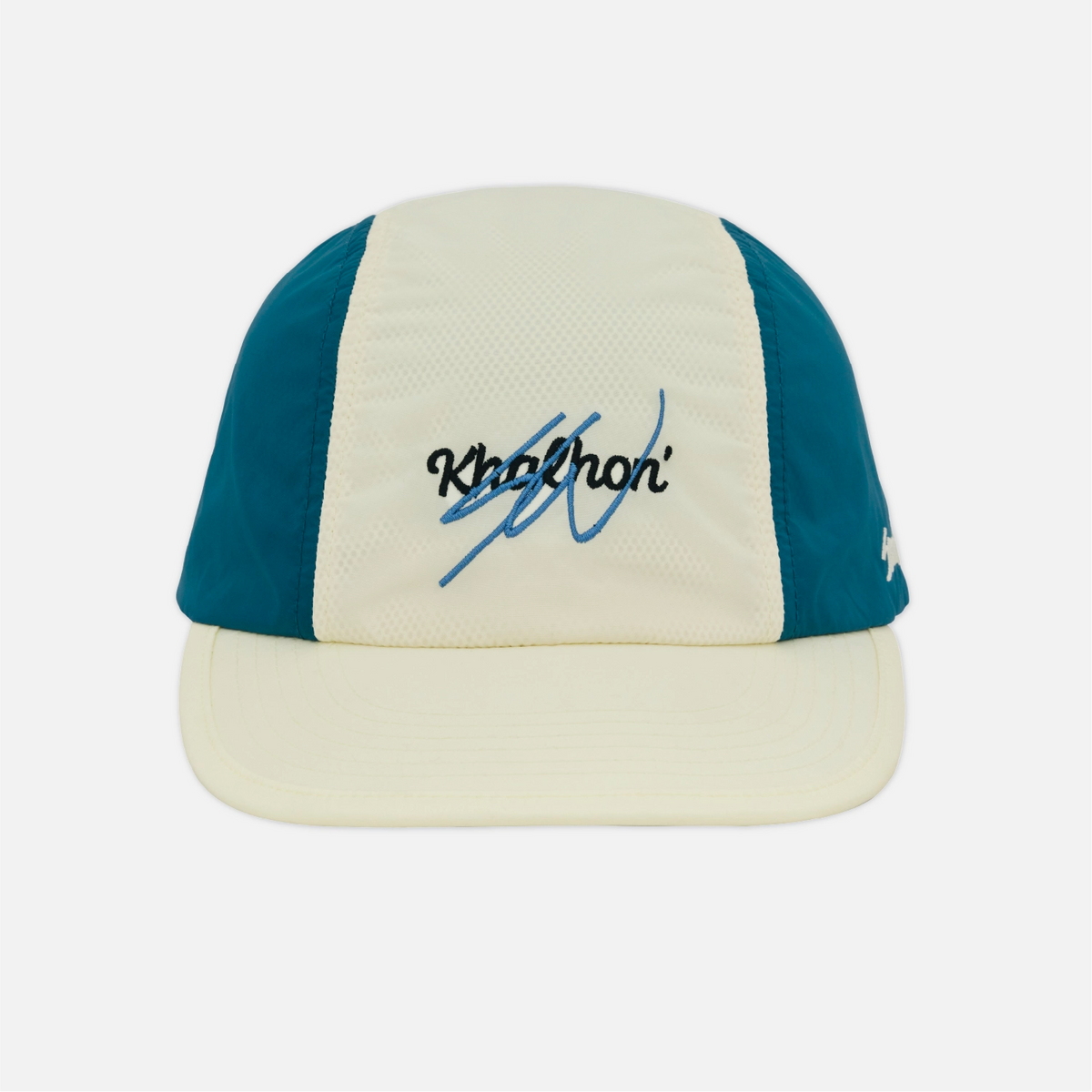 A 5-panel trucker cap with an off-white front panel and brim, teal blue side panels, and a black and blue embroidered signature on the front, shown against a light gray background.