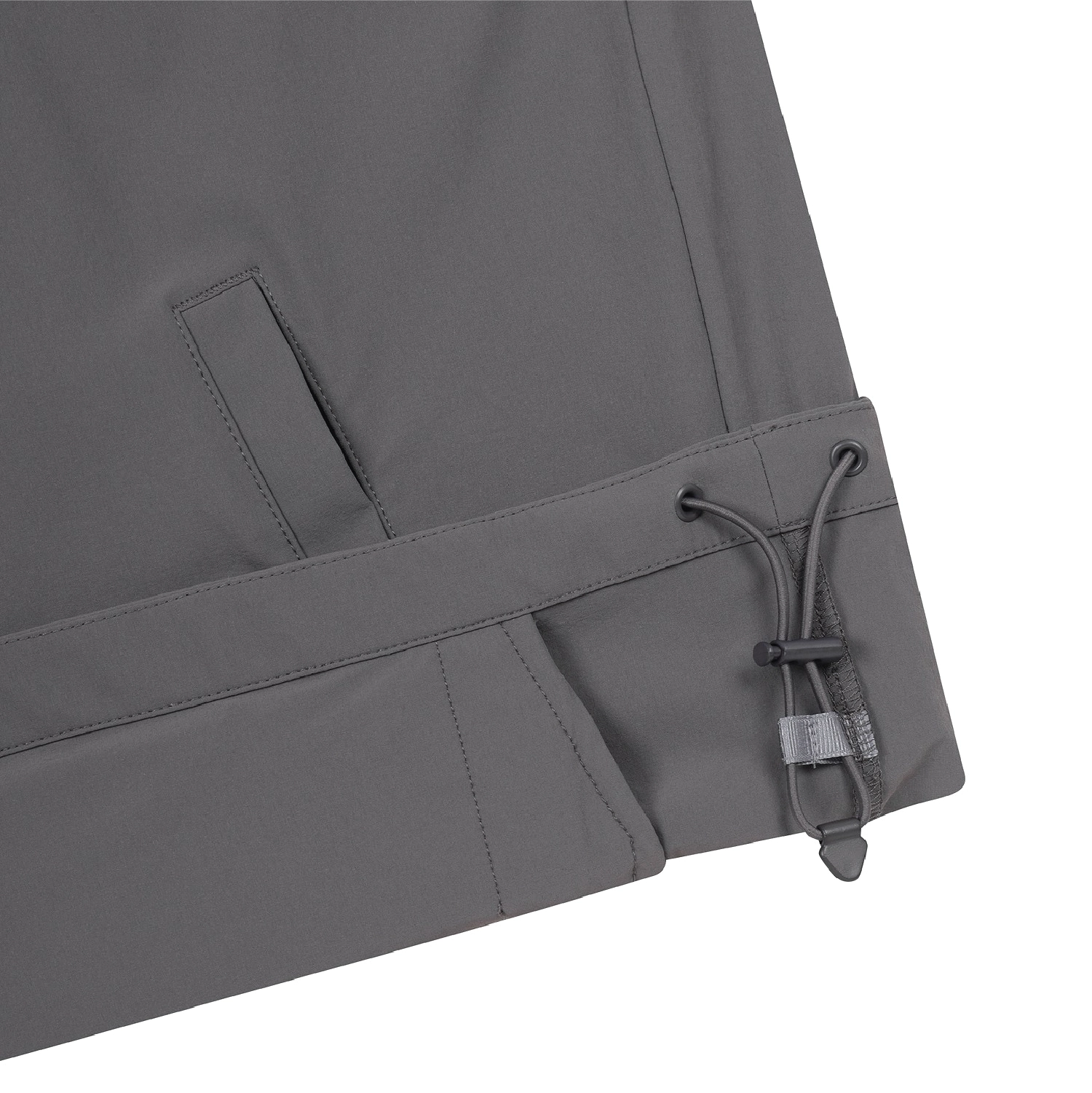 Close-up of the lower corner of dark gray outdoor pants showing a drawstring hem with a toggle closure, on a white background.