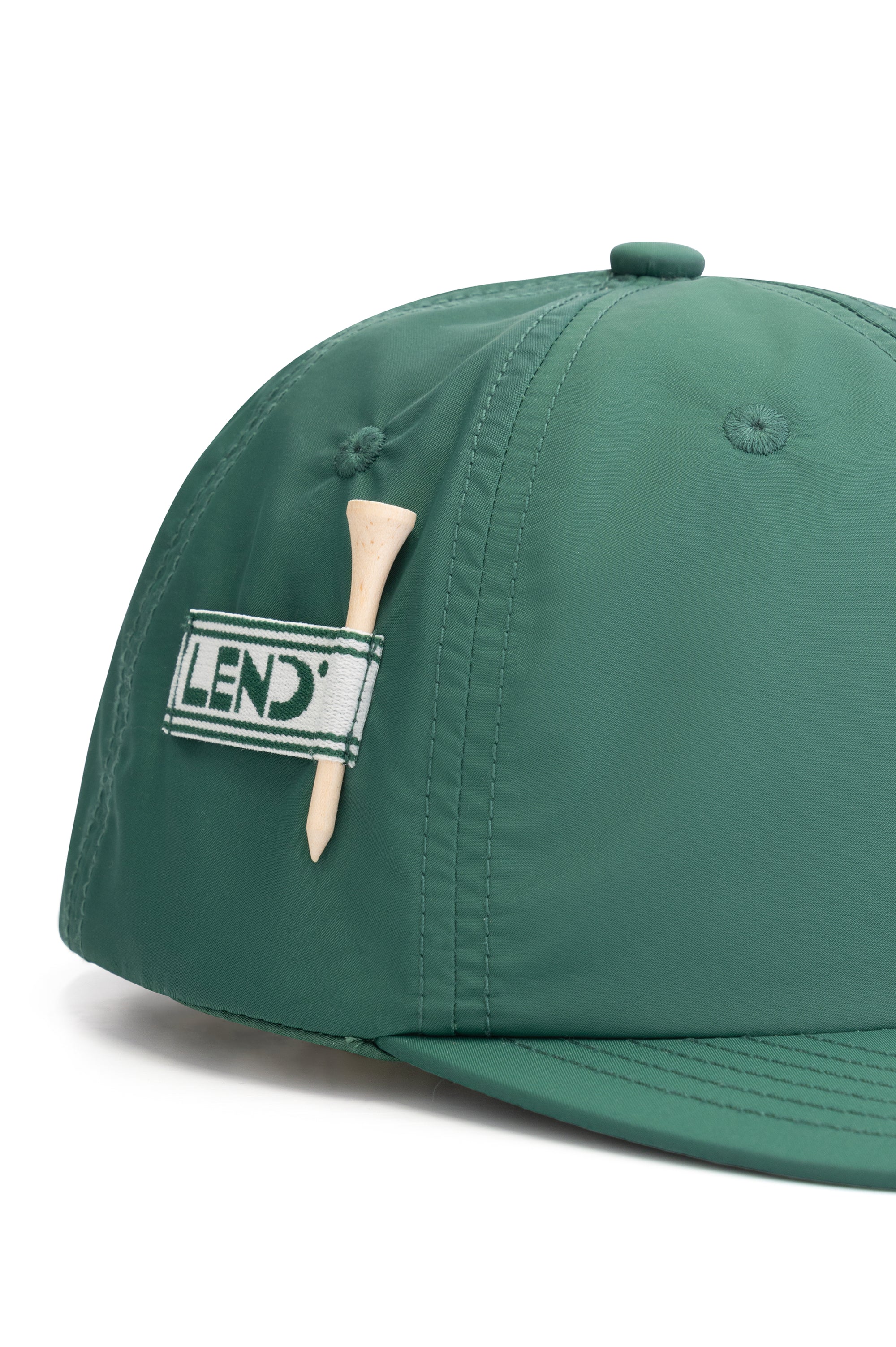Green water-repellent golf cap with structured panels, stretch fit, Lend patch logo, and a built-in wooden tee holder on the side.