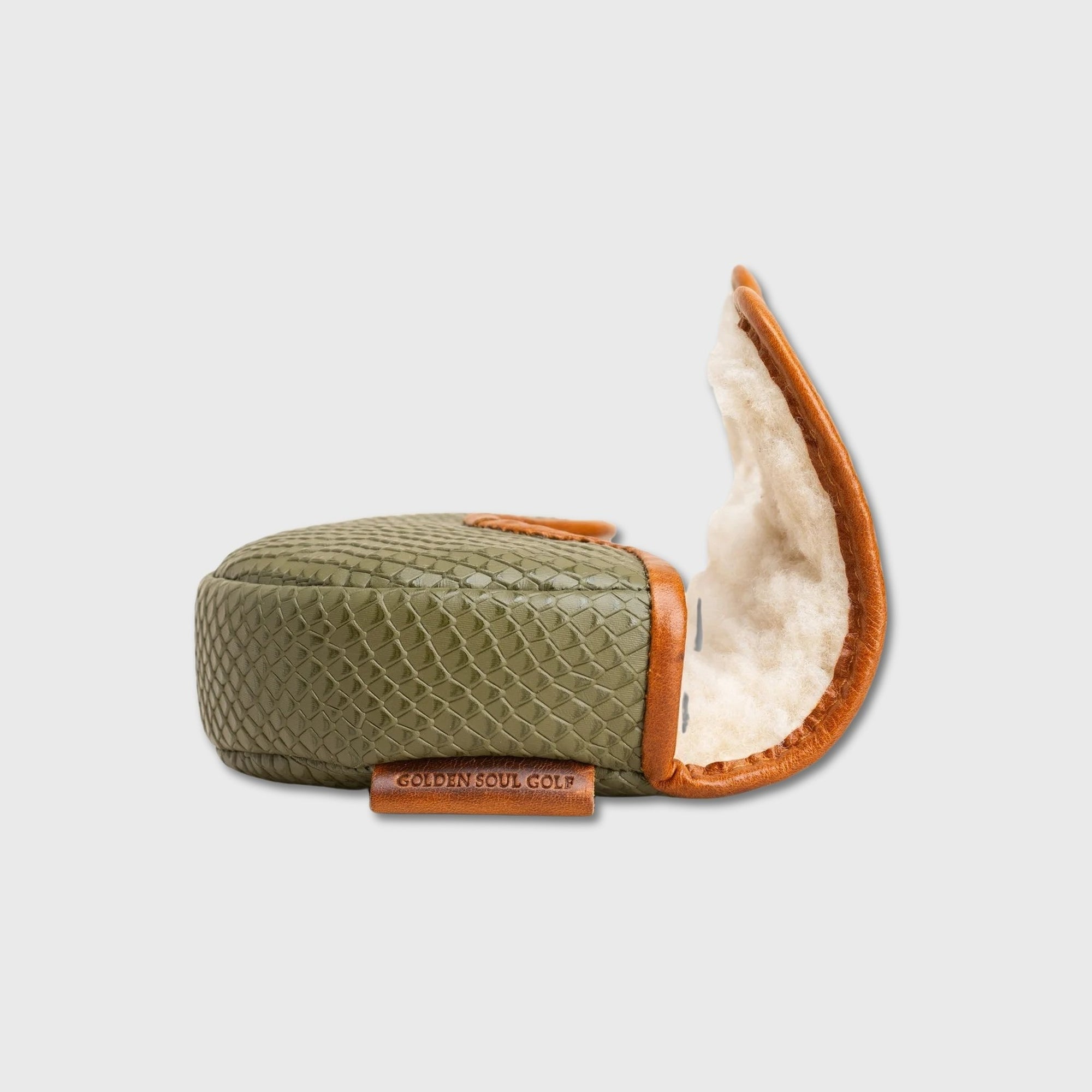 An olive green python-textured OZ1 putter cover shown open, featuring a warm brown leather trim and a plush cream-colored lining, with a small leather brand tag reading 'GOLDEN SOUL GOLF' on a light gray background.