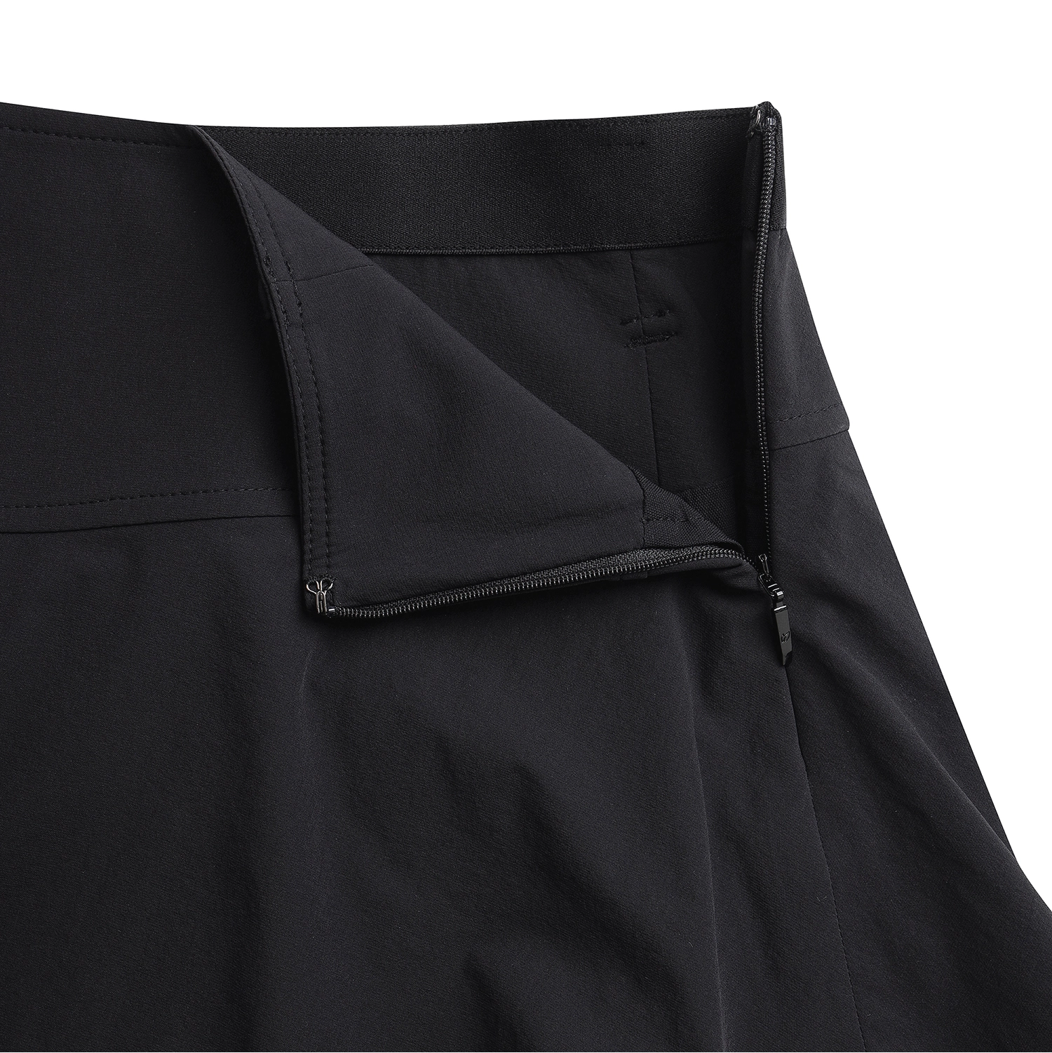 Close-up of a black zippered garment, showing the waistband, folded flap, and zipper pull on a plain white background.