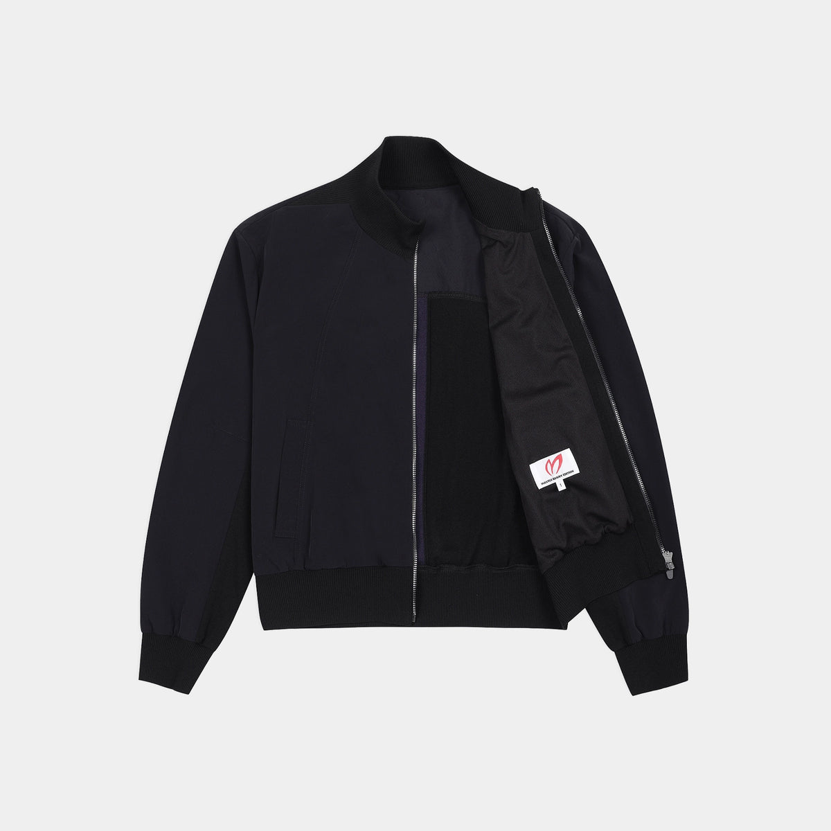 A black zip-up bomber jacket with a stand collar, ribbed cuffs and hem, featuring a black interior lining and a small white brand patch on the sleeve.
