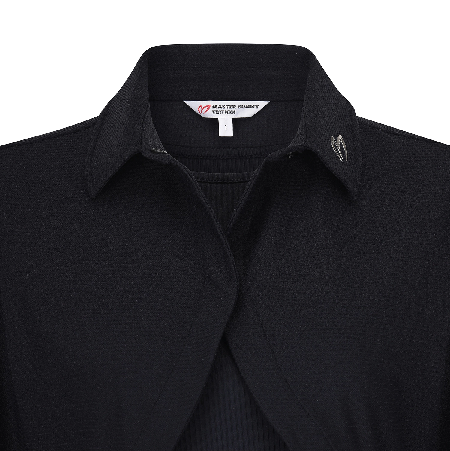 Close-up of a black ribbed knit collared shirt by Master Bunny Edition, showing the inner neck label and a small silver-toned logo on the chest.