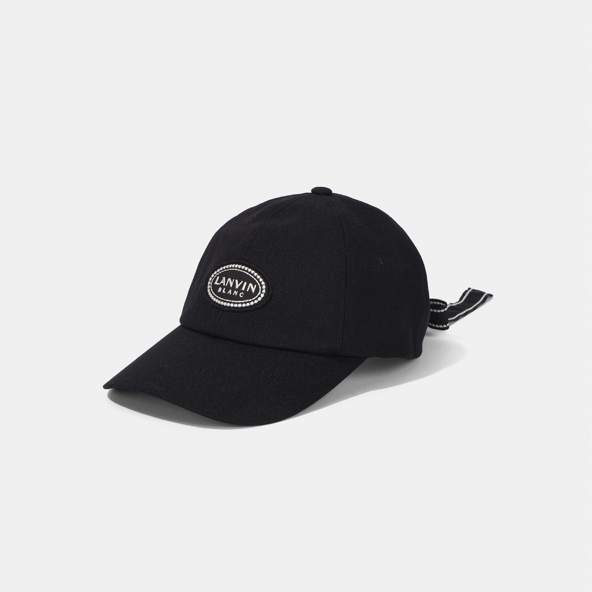 A black baseball cap with a curved brim and a small white embroidered oval 'LANVIN BLANC' logo on the front, shown on a light gray background.