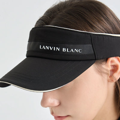 A close-up of a woman wearing a black visor with white trim and the brand name 'LANVIN BLANC' printed on the front band.