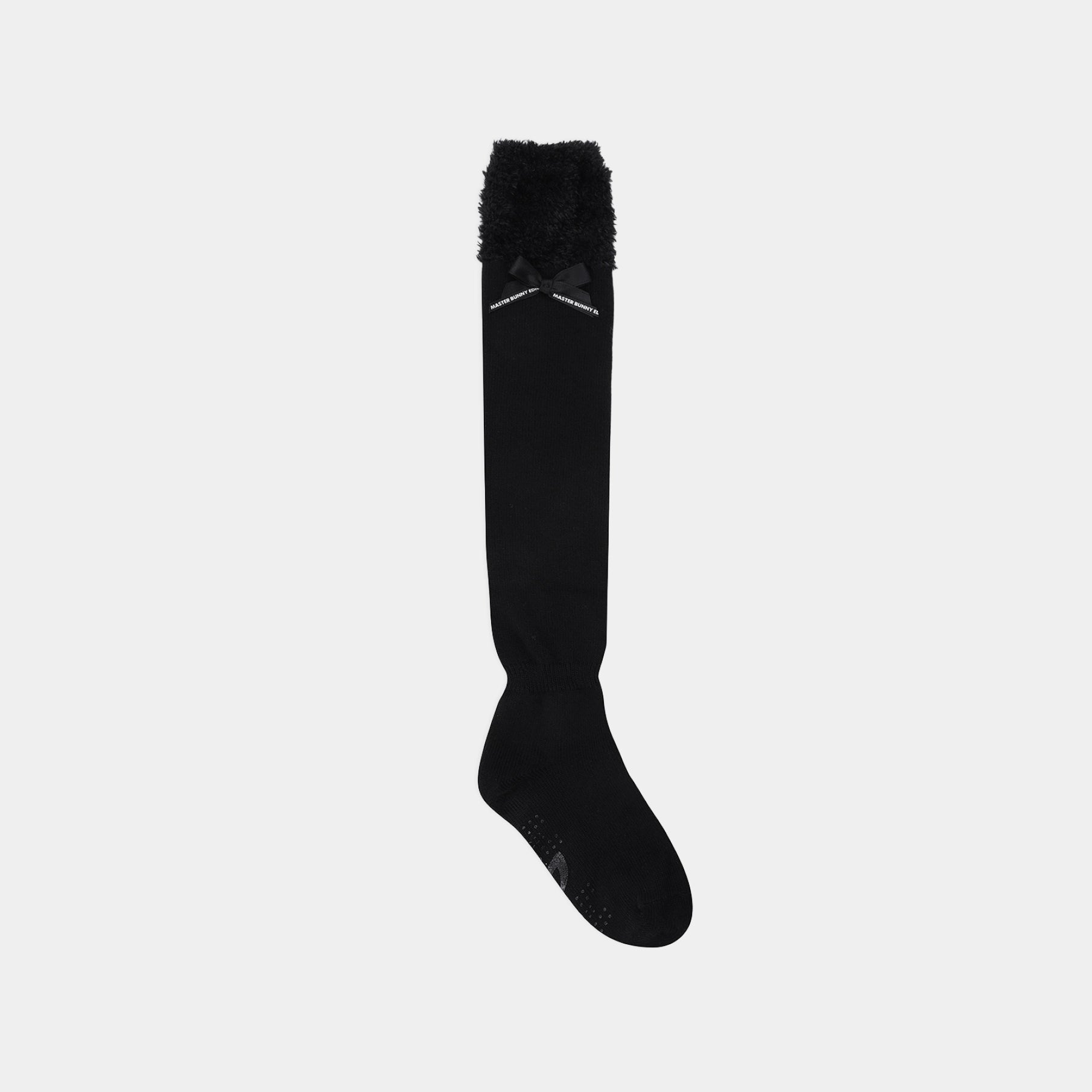 A single black over-the-knee sock with a fluffy black trim at the top and a small black bow detail, shown against a solid light gray background.