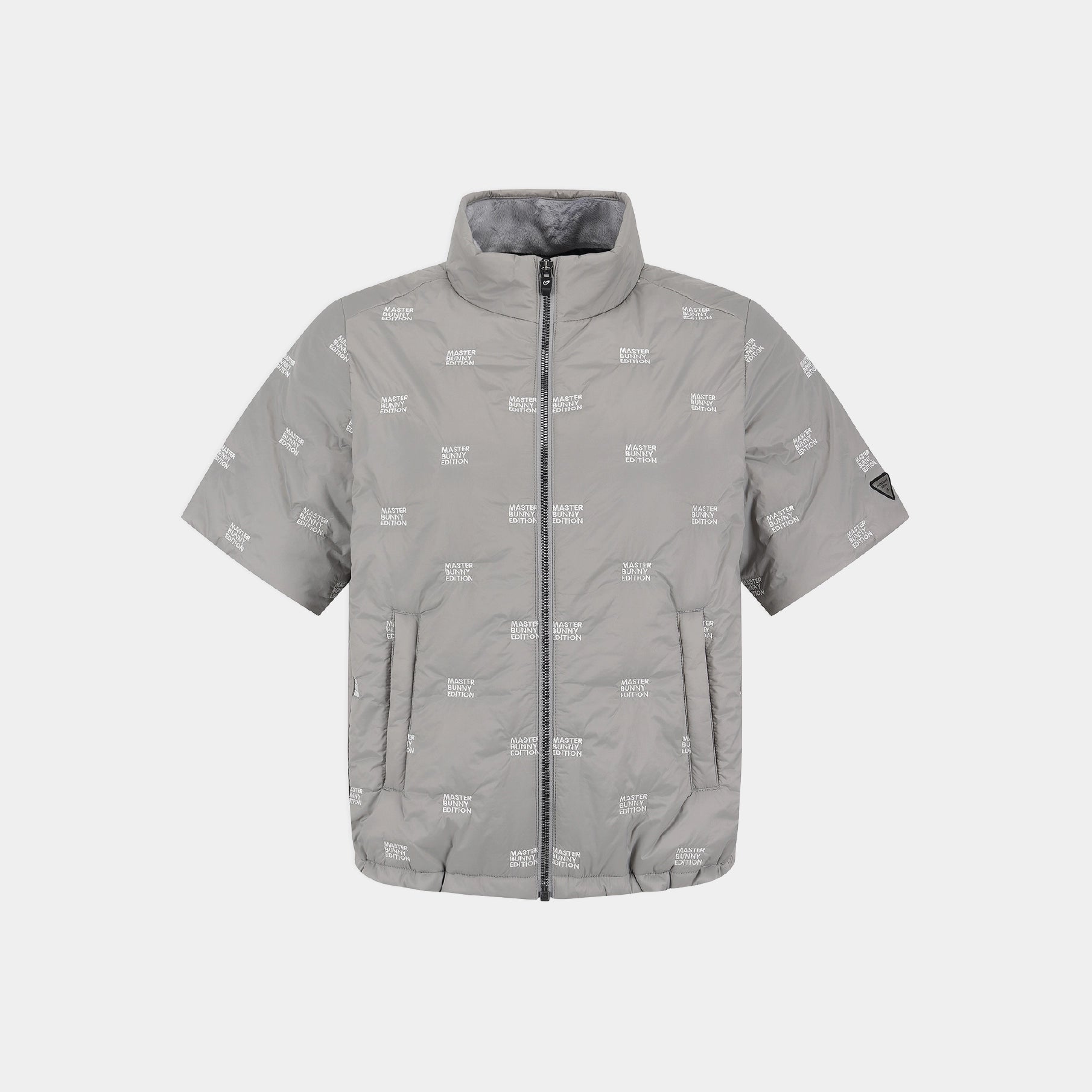 A light gray short-sleeve puffer jacket with an all-over white 'MASTER BUNNY EDITION' text print, a full-length front zipper, and a stand-up collar, shown against a light gray background.