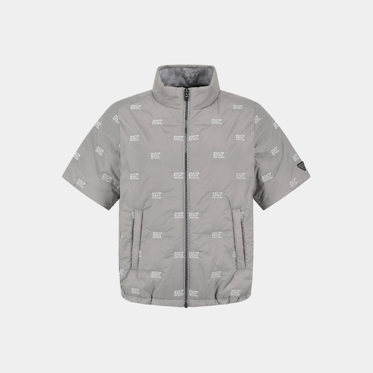 A light gray short-sleeve puffer jacket with an all-over white 'MASTER BUNNY EDITION' text print, a full-length front zipper, and a stand-up collar, shown against a light gray background.