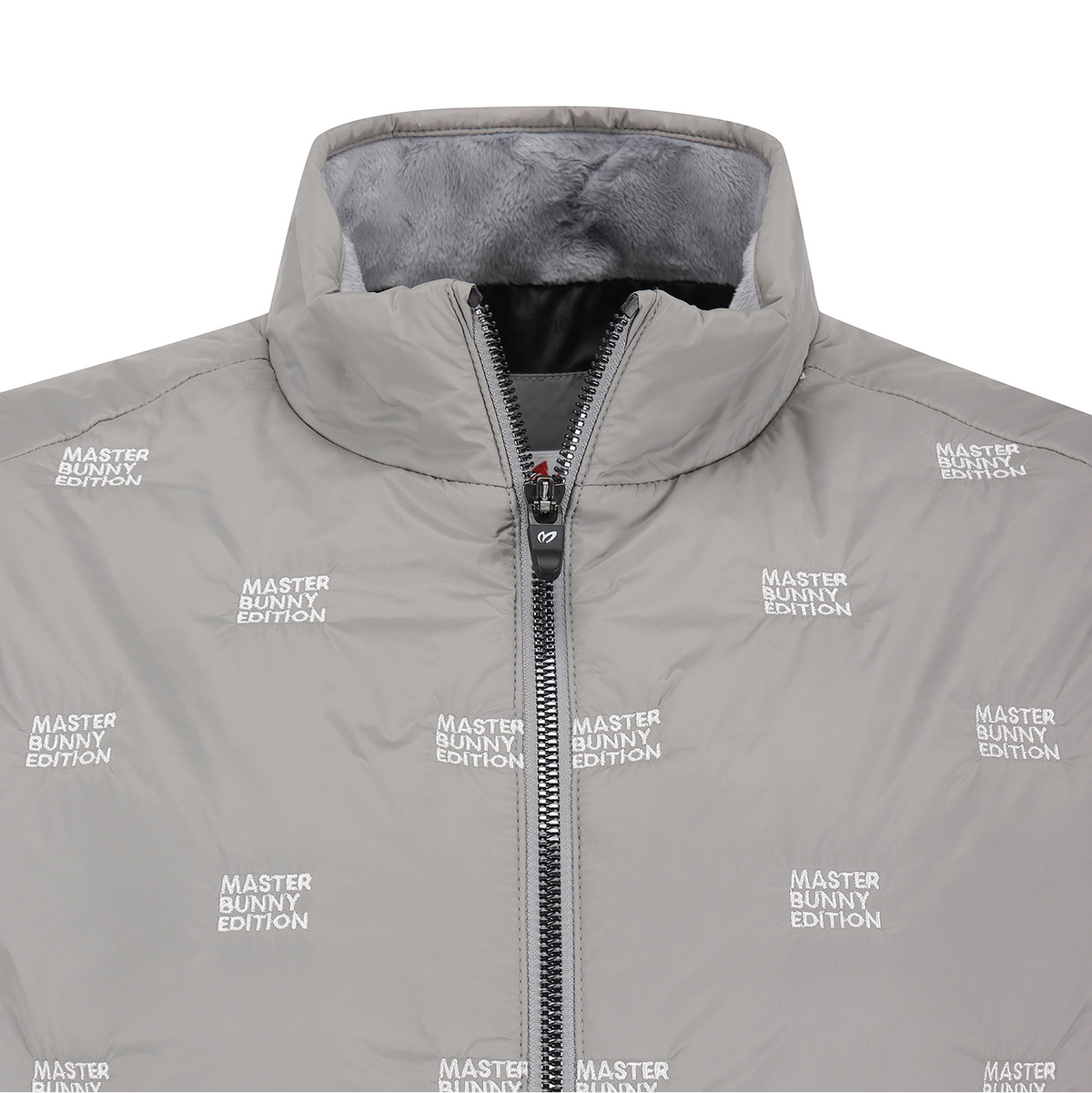 A close-up of a light gray puffer jacket with a high collar, black zipper, and an all-over white 'MASTER BUNNY EDITION' text print. The interior lining is a soft gray fleece.