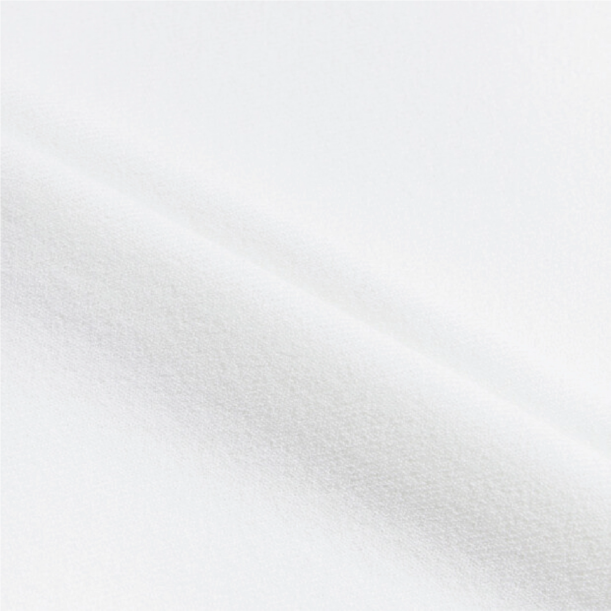 A close-up of white textured fabric with soft diagonal folds and a fine woven surface.