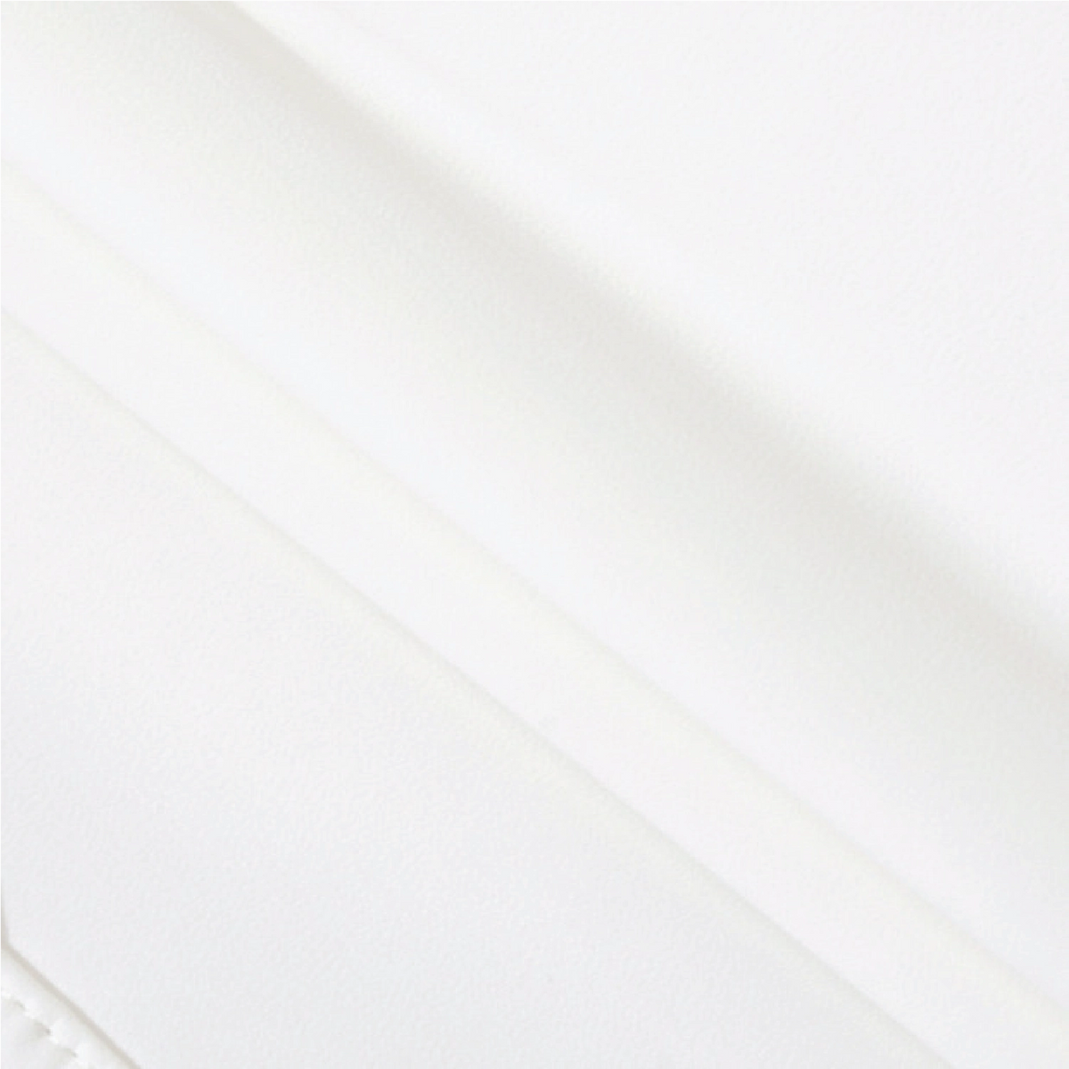 A close-up of a smooth, off-white leather or faux leather material with soft diagonal folds and a subtle stitched edge visible in the bottom-left corner.