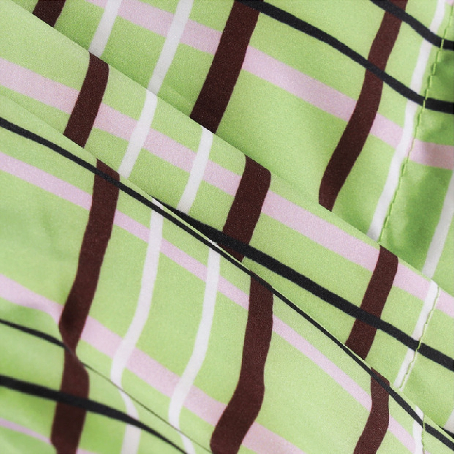 A close-up of a draped fabric with a plaid pattern featuring light green, pink, dark brown, and thin black stripes.