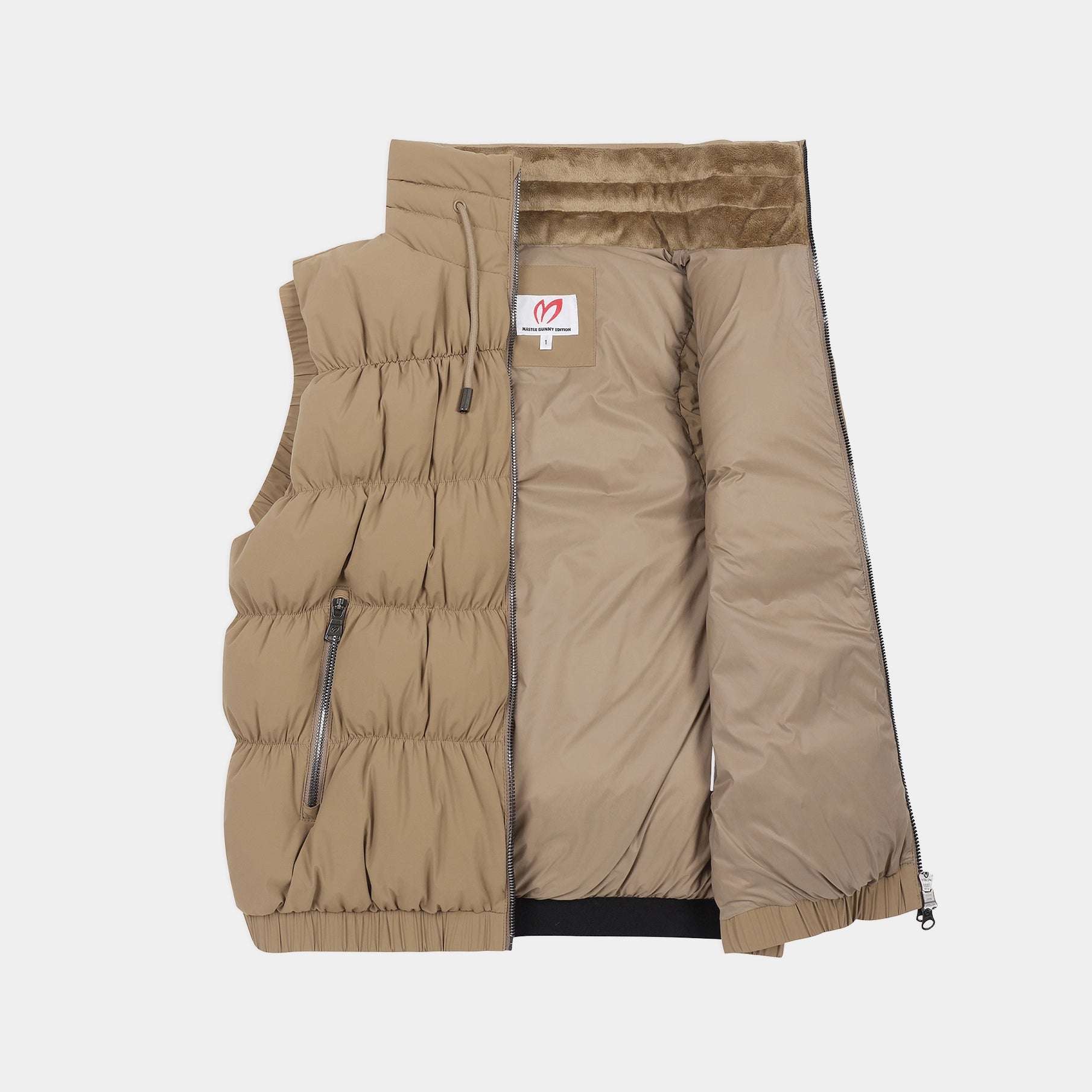A tan quilted puffer vest shown flat against a light gray background, with its front zipper opened to reveal a plush tan lining. A small rectangular brand patch is visible on the chest.