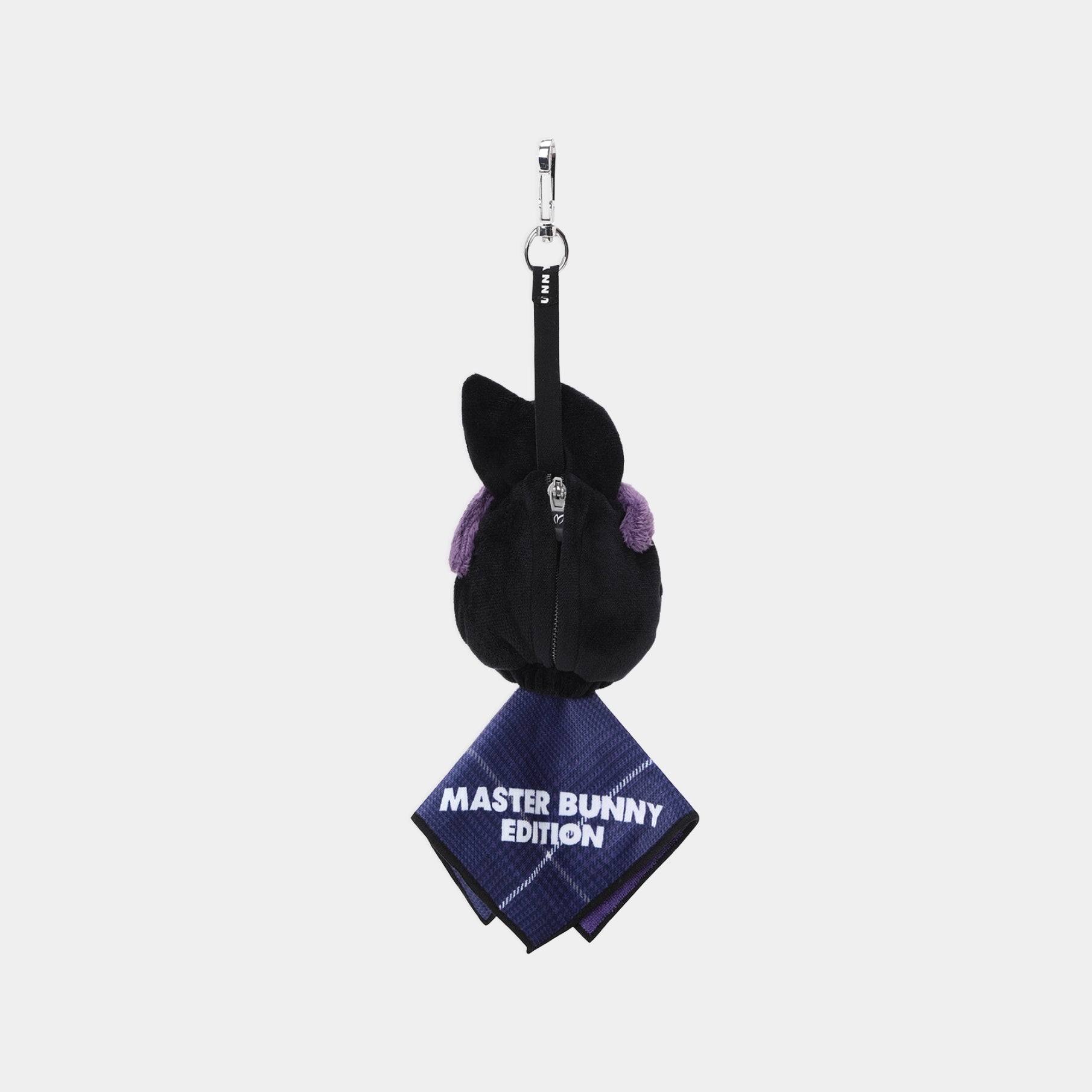 A plush black bunny head keychain or bag charm with purple inner ears, attached to a black strap and silver key ring, with a navy plaid bandana reading 'MASTER BUNNY EDITION' hanging below on a light gray background.