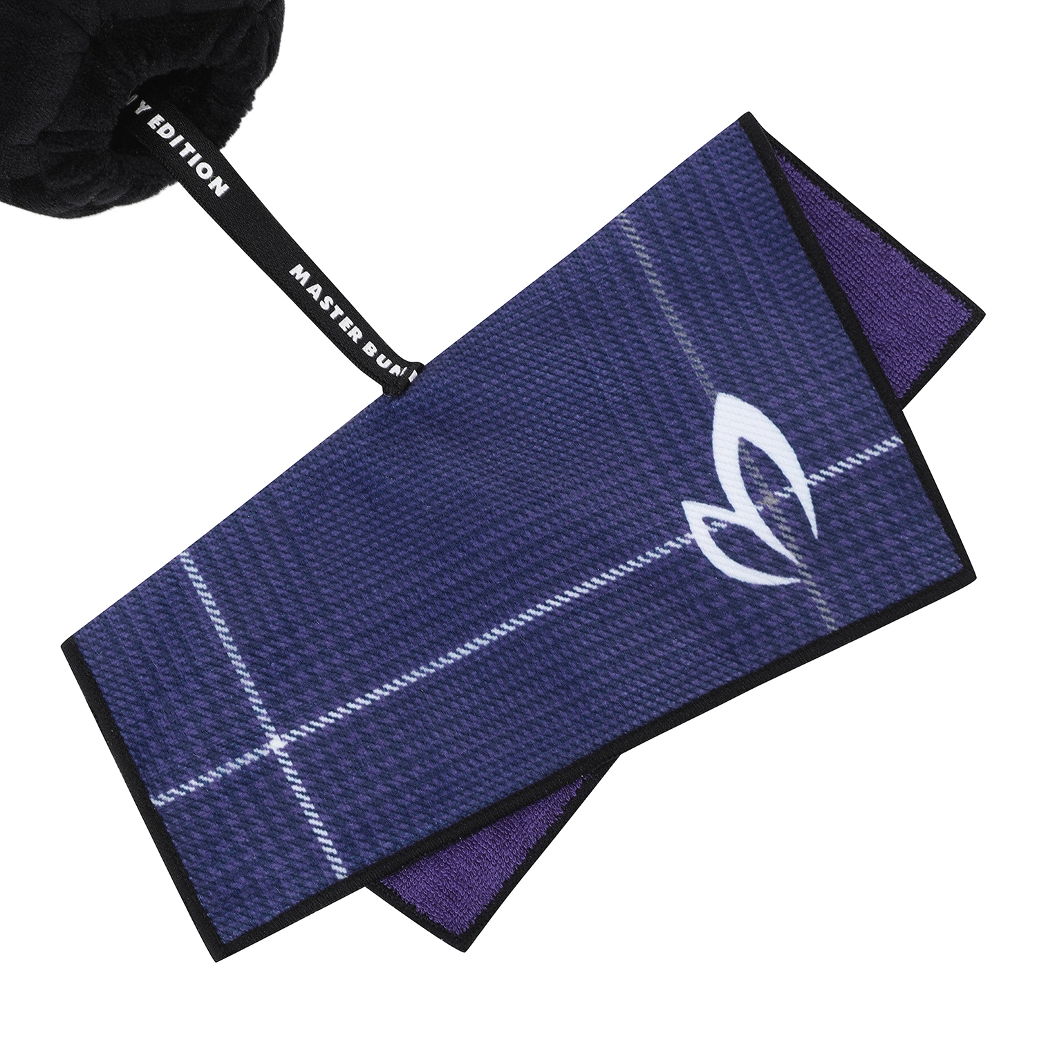 A close-up of a woven golf towel in dark navy blue with a purple reverse side, white grid lines, and a white leaf logo. A black strap with white text reading 'MASTER BUNNY EDITION' is attached.