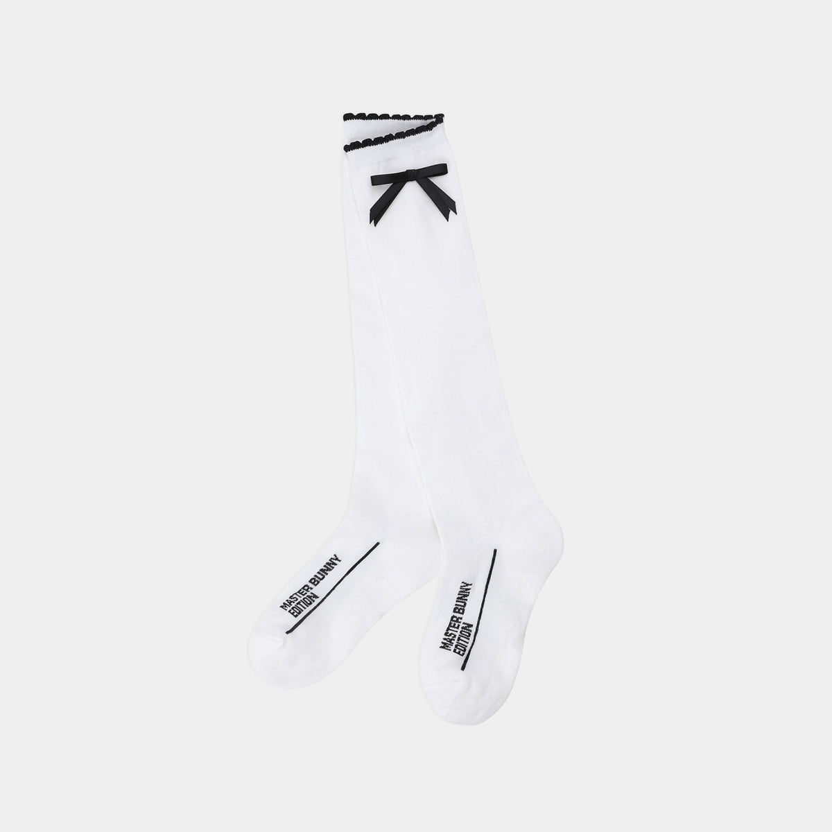 A pair of white knee-high socks with black trim, featuring a black bow at the top and black text branding near the toes, shown against a light gray background.