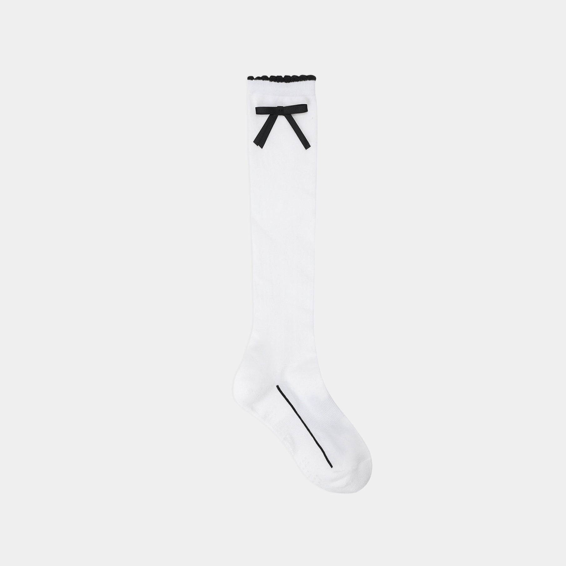 A single white knee-high sock with a black bow detail at the top cuff and a thin black line running from the toe toward the foot, shown against a plain light gray background.