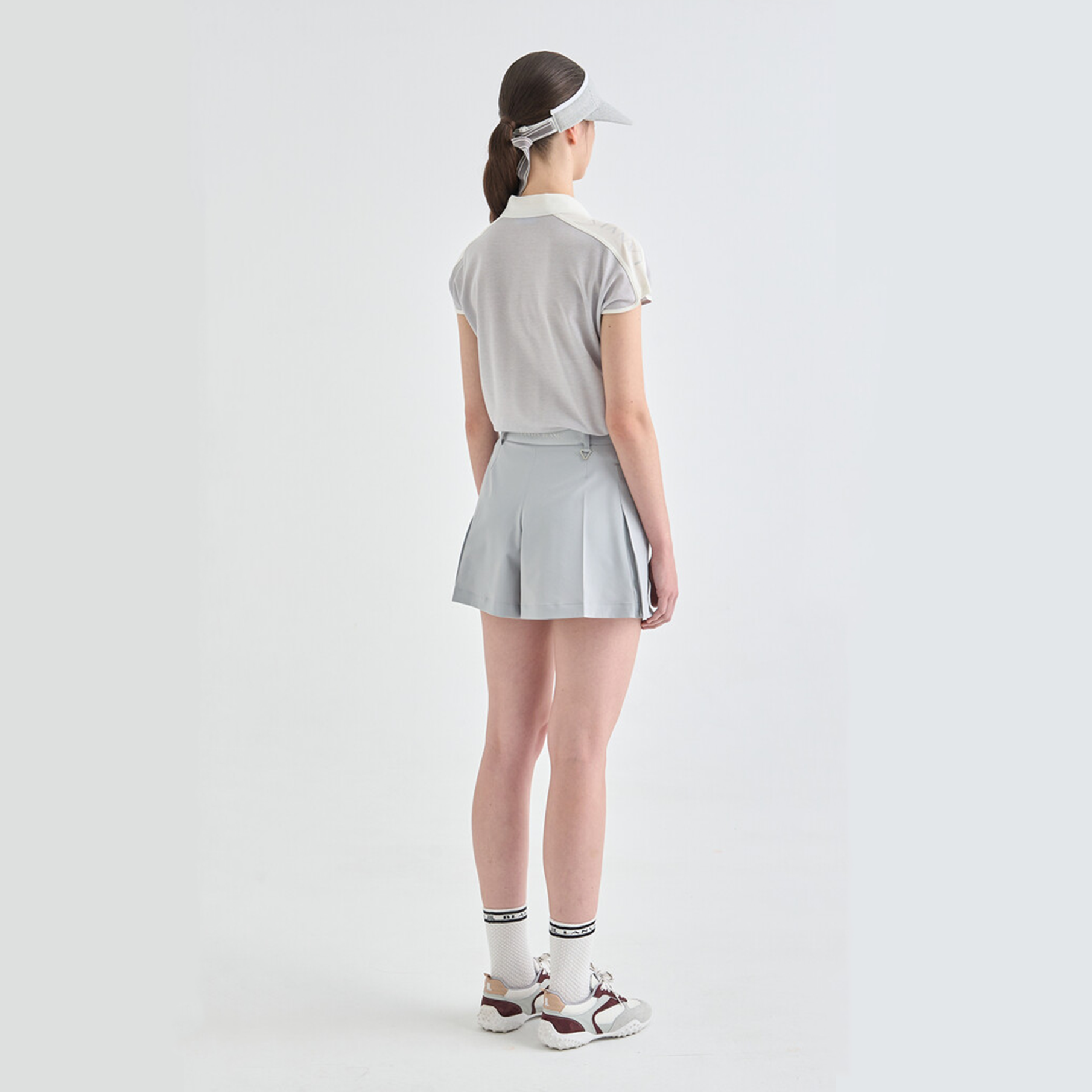 Person wearing a gray tennis outfit with a visor on a white background