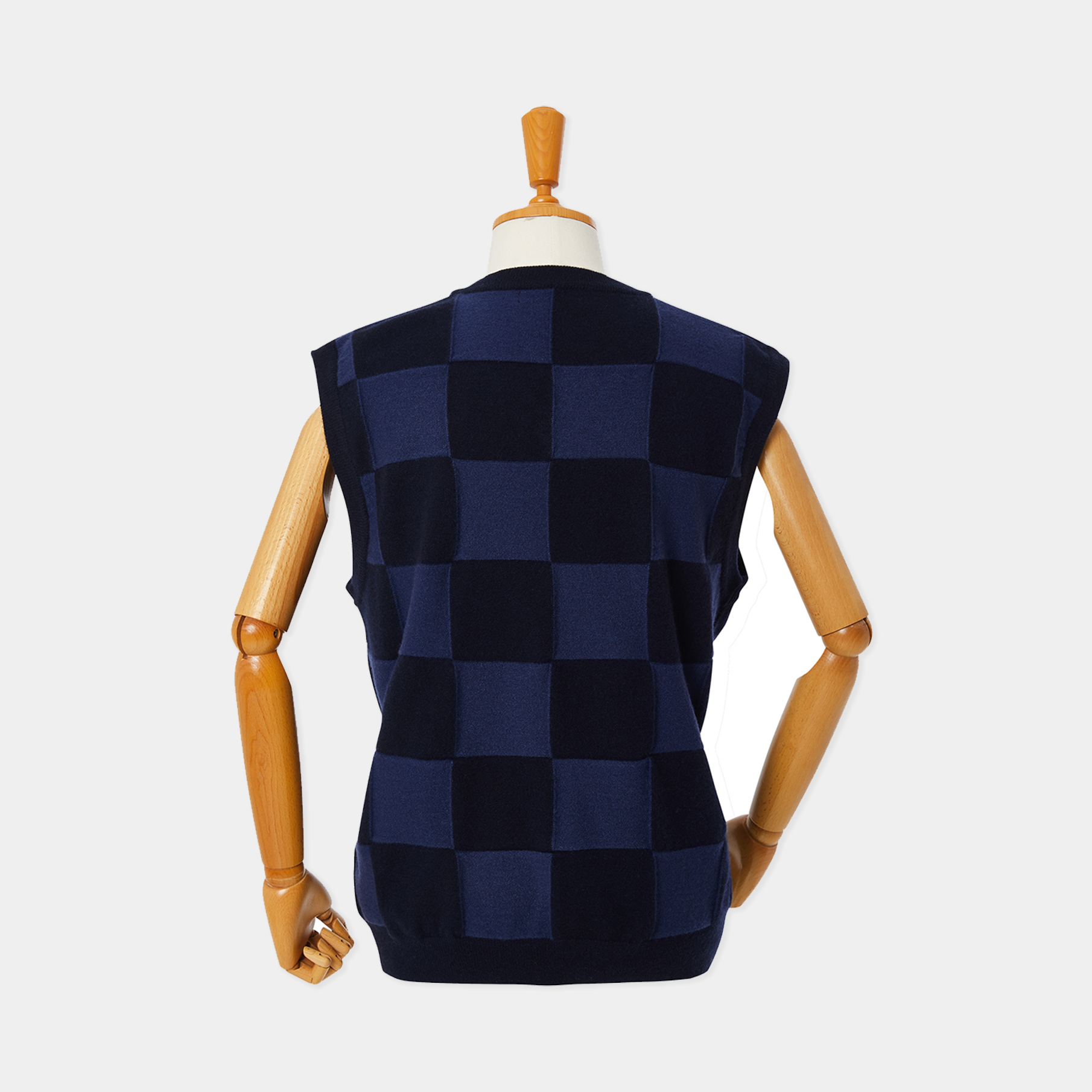 Checkered vest on a wooden mannequin against a white background