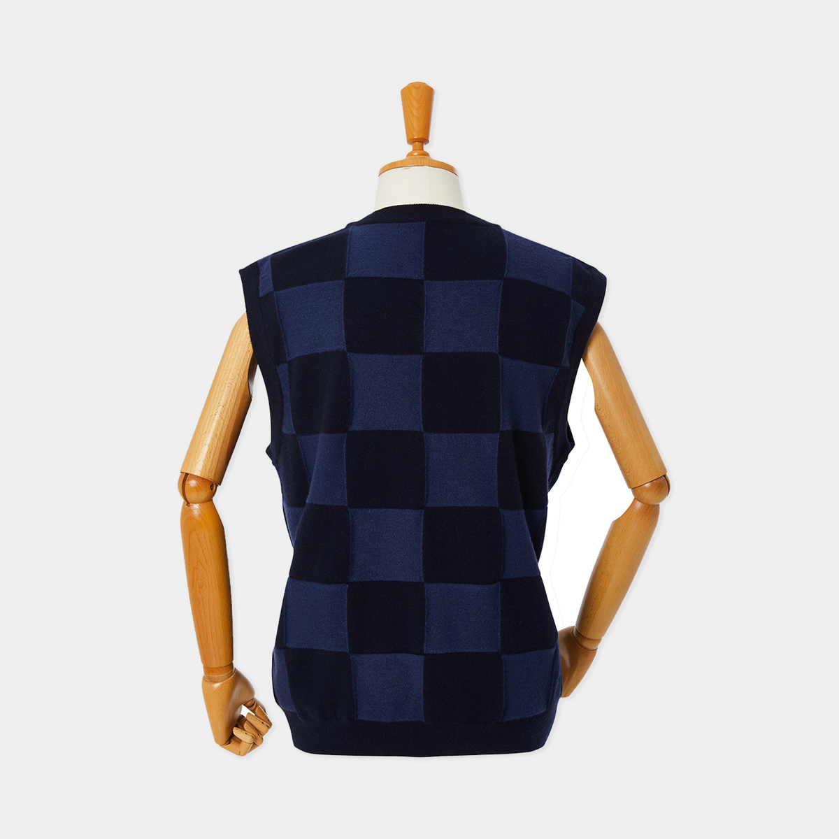 Checkered vest on a wooden mannequin against a white background