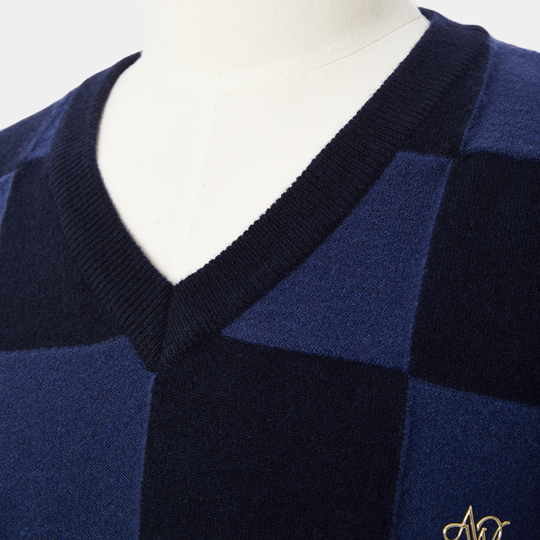 Navy blue checkered cardigan on a mannequin with a brand logo.
