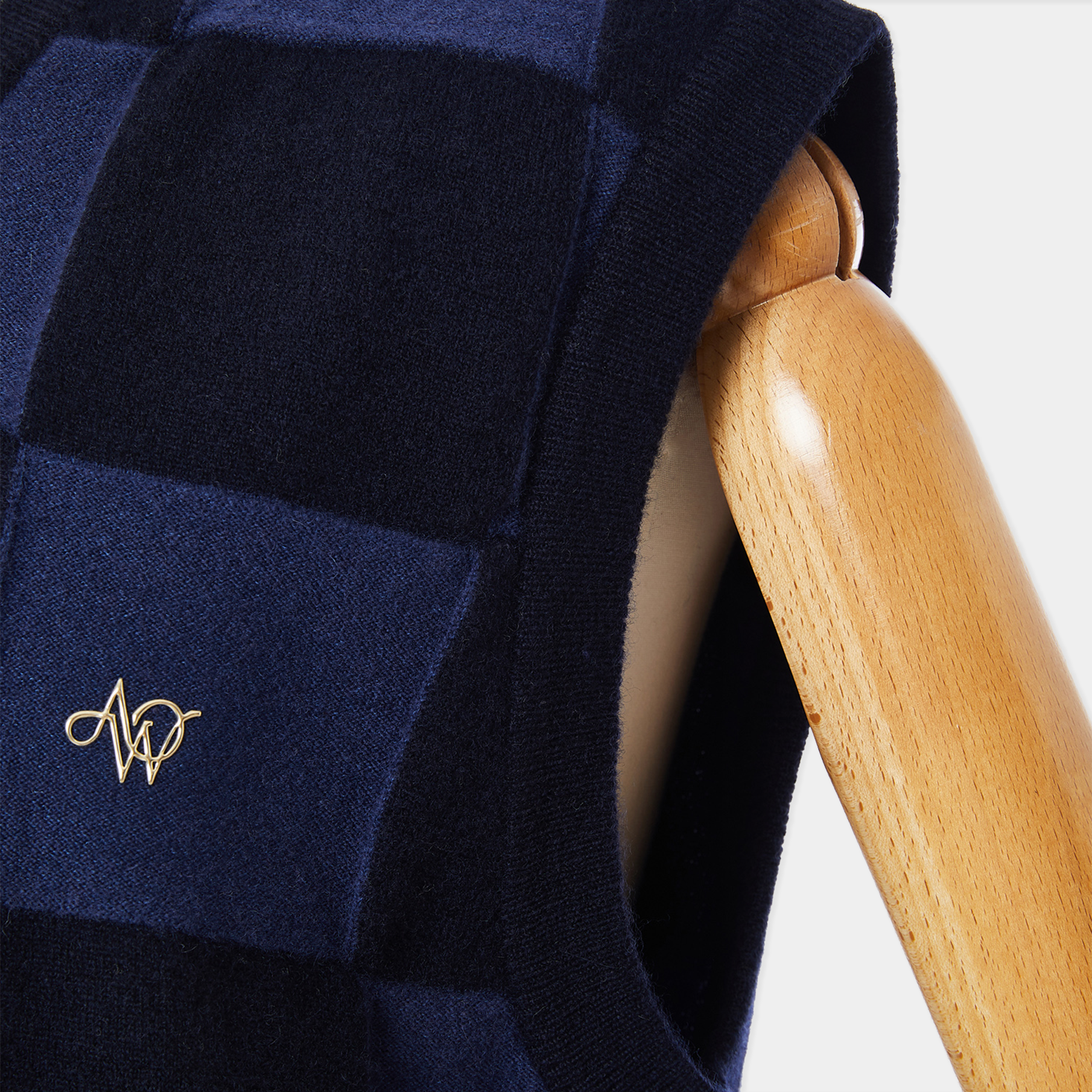 Navy blue quilted jacket with a gold logo on a wooden chair