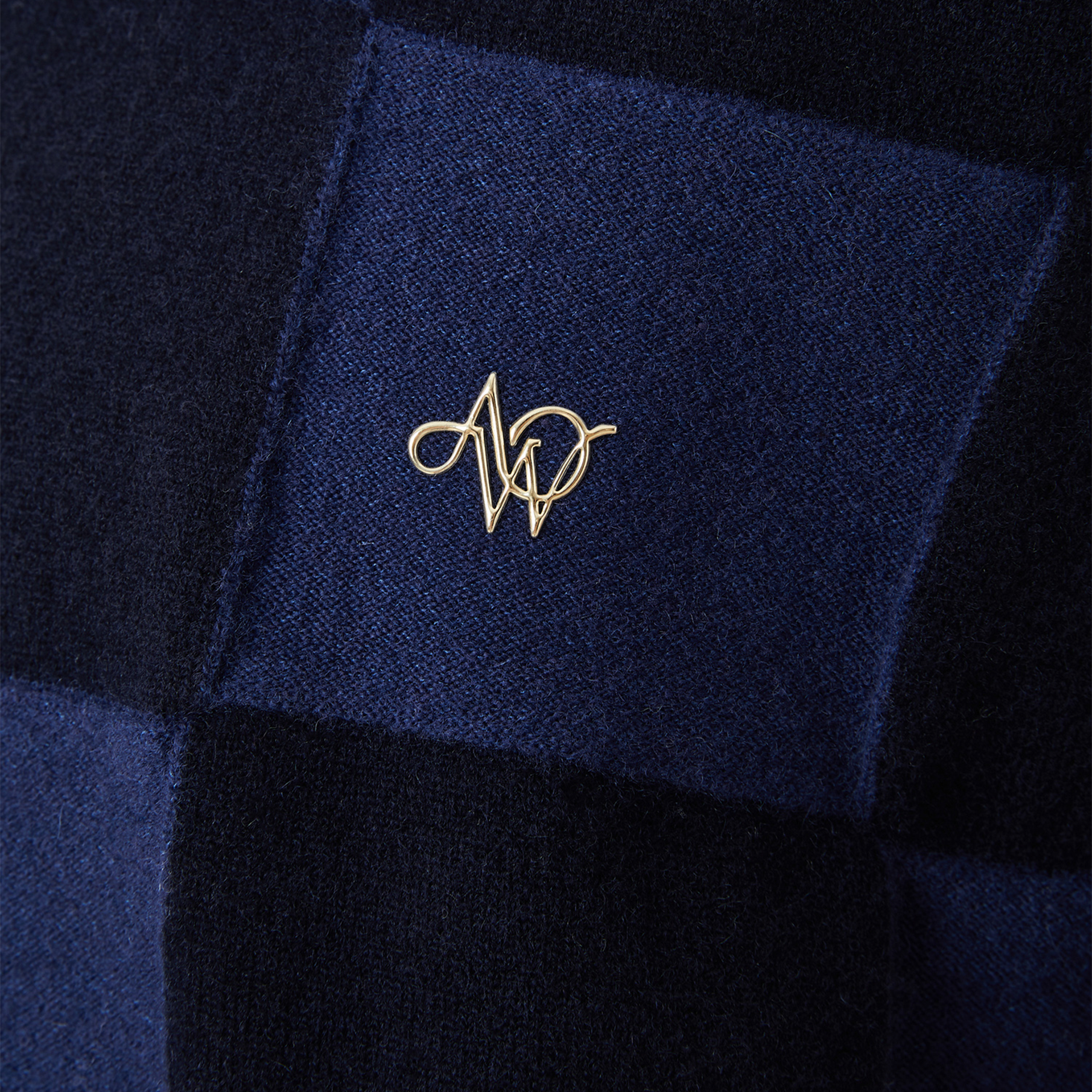Close-up of a navy blue fabric with a gold logo on a dark background