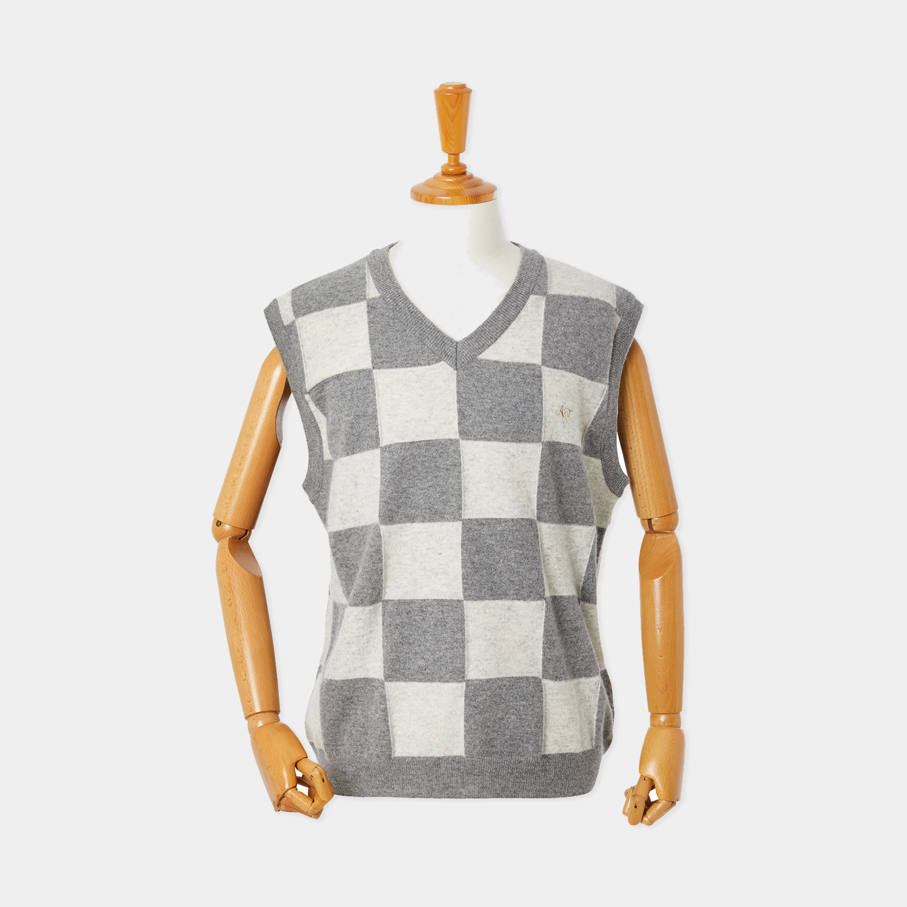 Checkered sleeveless sweater on a mannequin against a white background