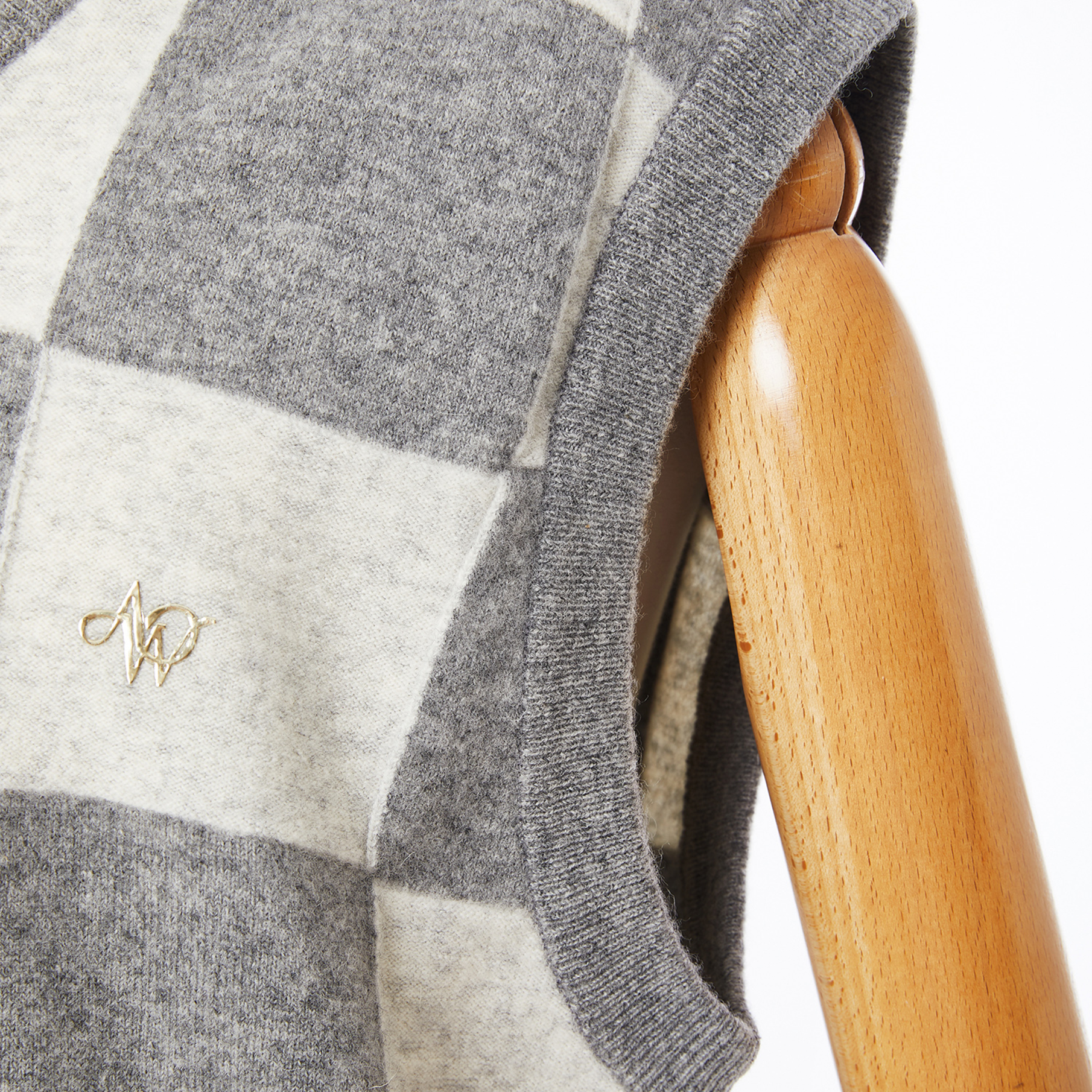 Gray and white checkered sweater vest on a wooden mannequin with a visible brand logo.