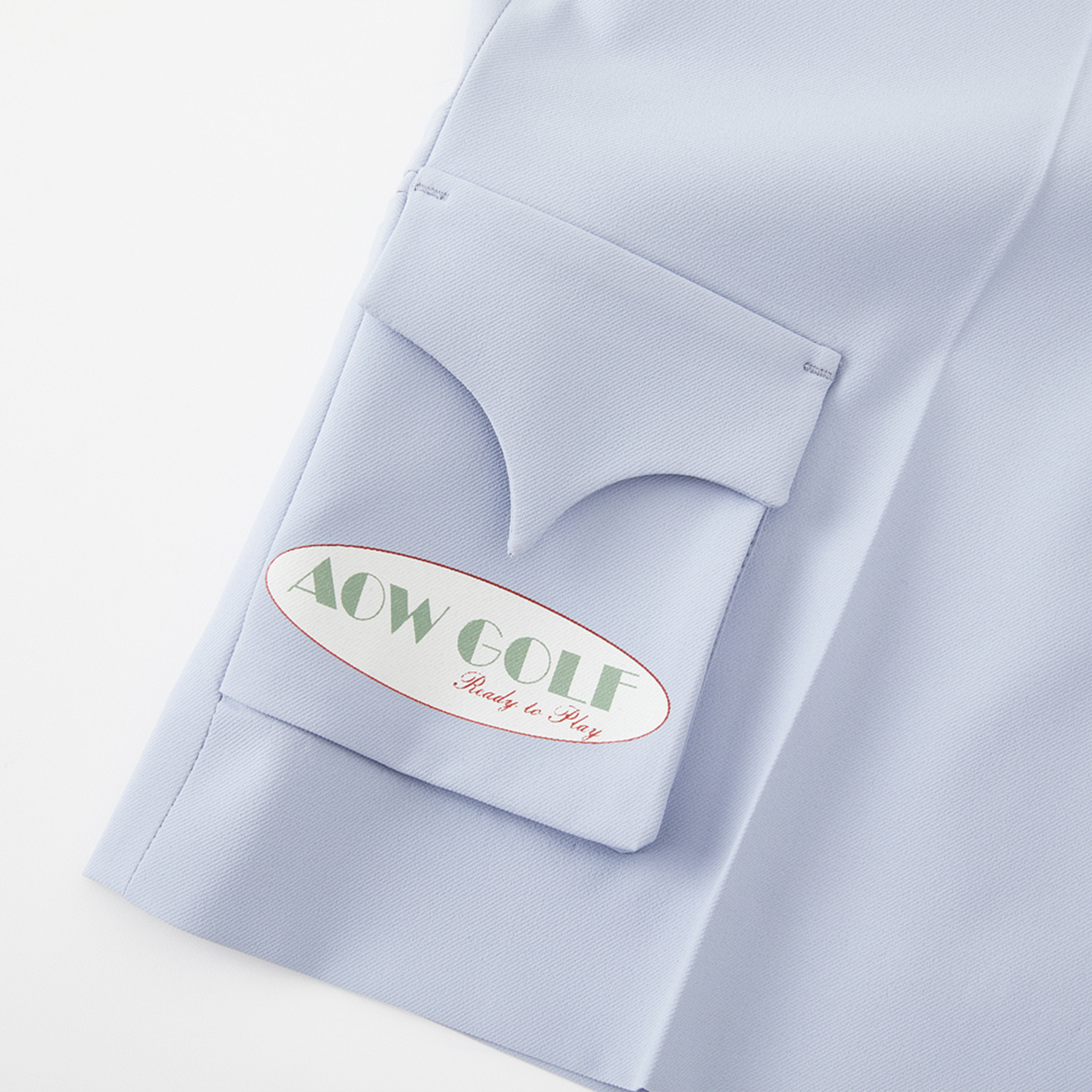 Light blue shirt with a pocket emblem displaying 'AOW GOLF Ready to Play'.