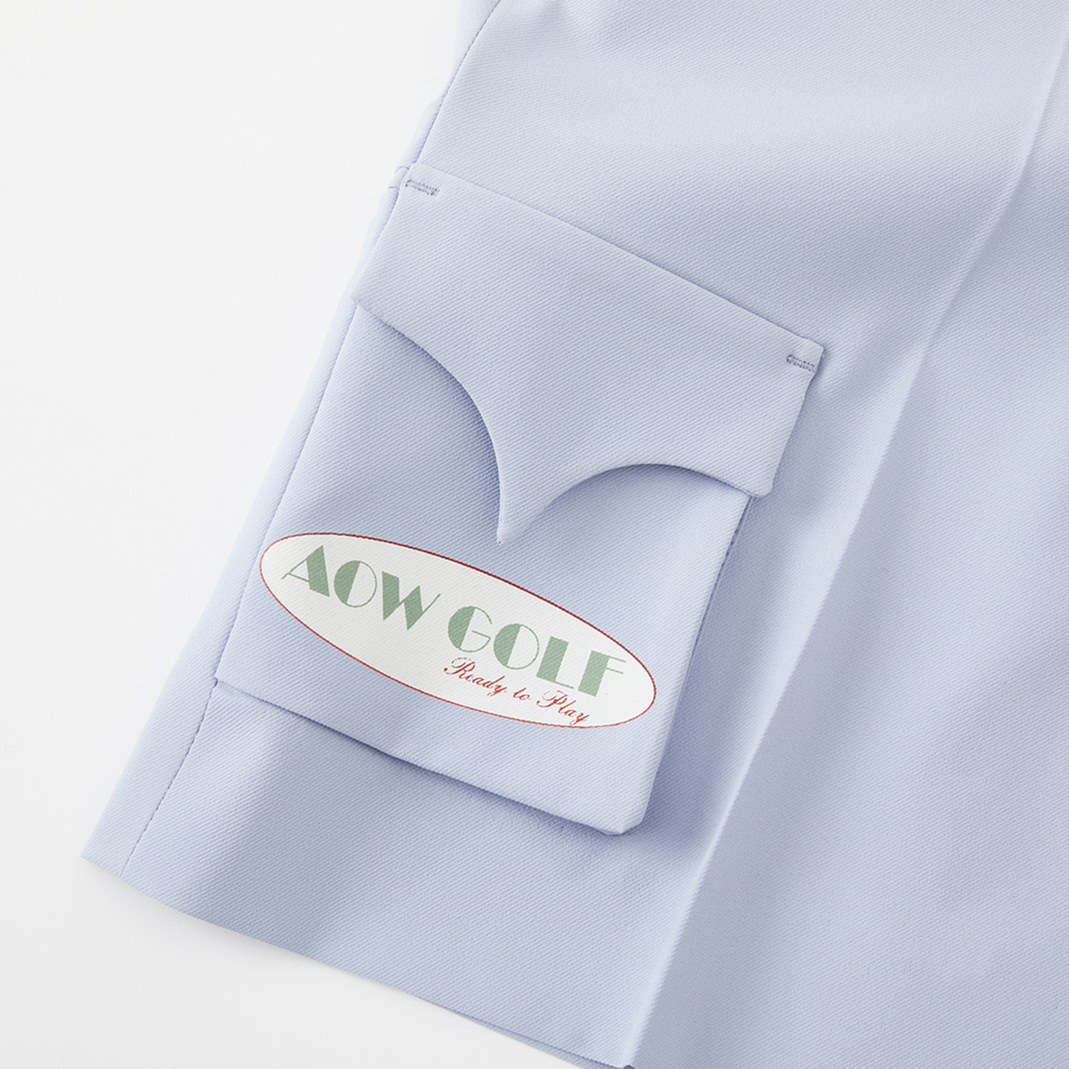 Light blue shirt with a pocket emblem displaying 'AOW GOLF Ready to Play'.