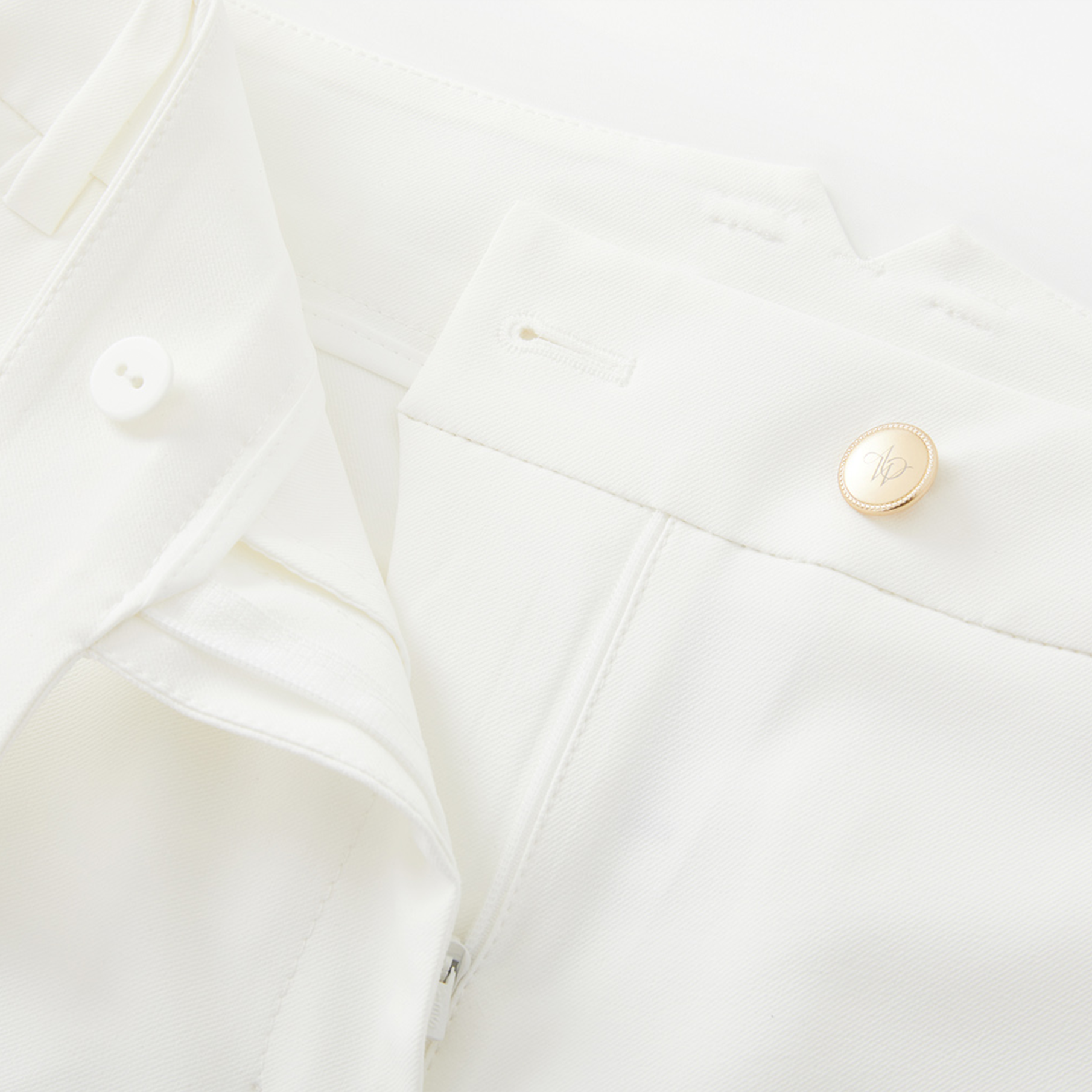 Close-up of a white garment with gold buttons on a light background
