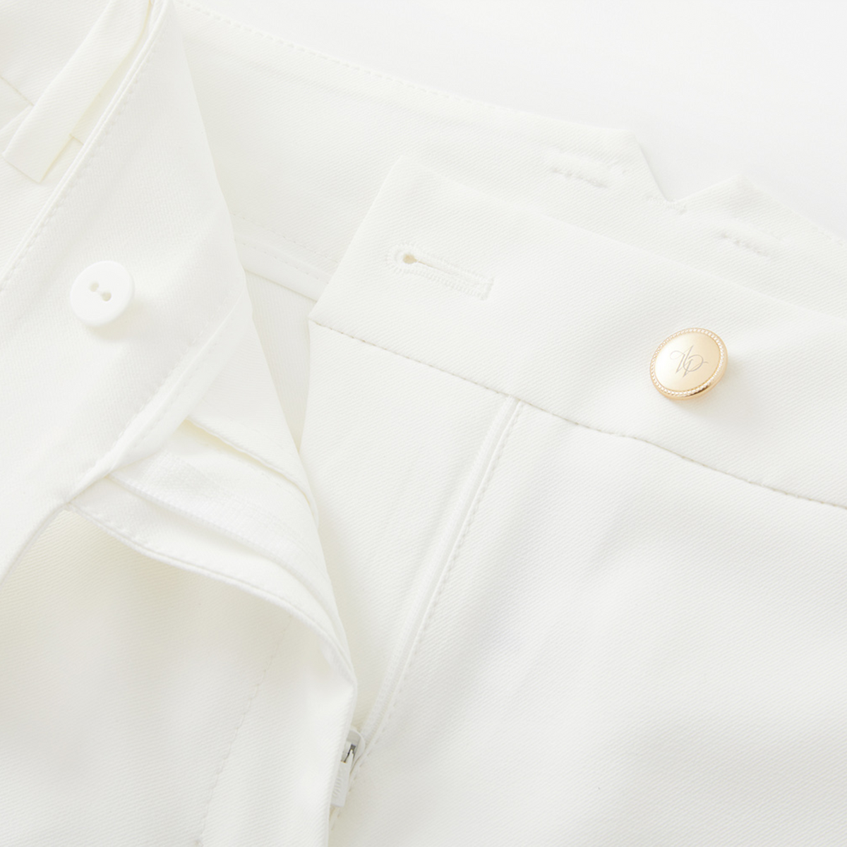 Close-up of a white garment with gold buttons on a light background