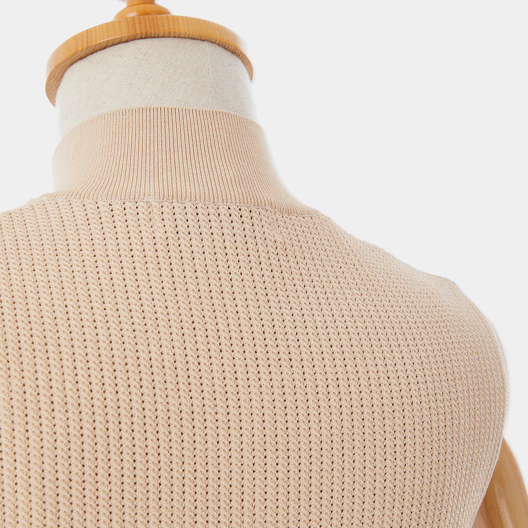 Beige knit sweater on a mannequin with a white background